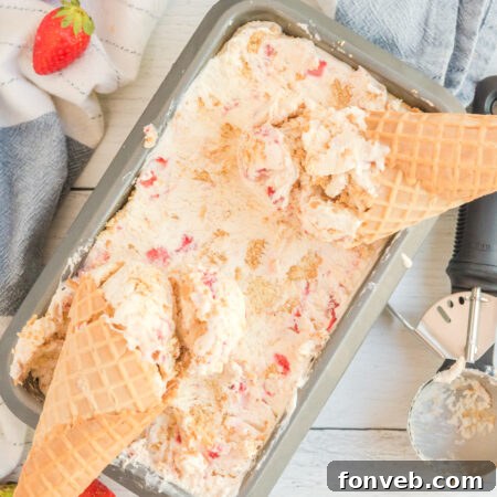 Frozen Strawberry Cheesecake Dream 23 Overhead view of a pan full of Strawberry Cheesecake Ice Cream with two waffle cones laying on top.