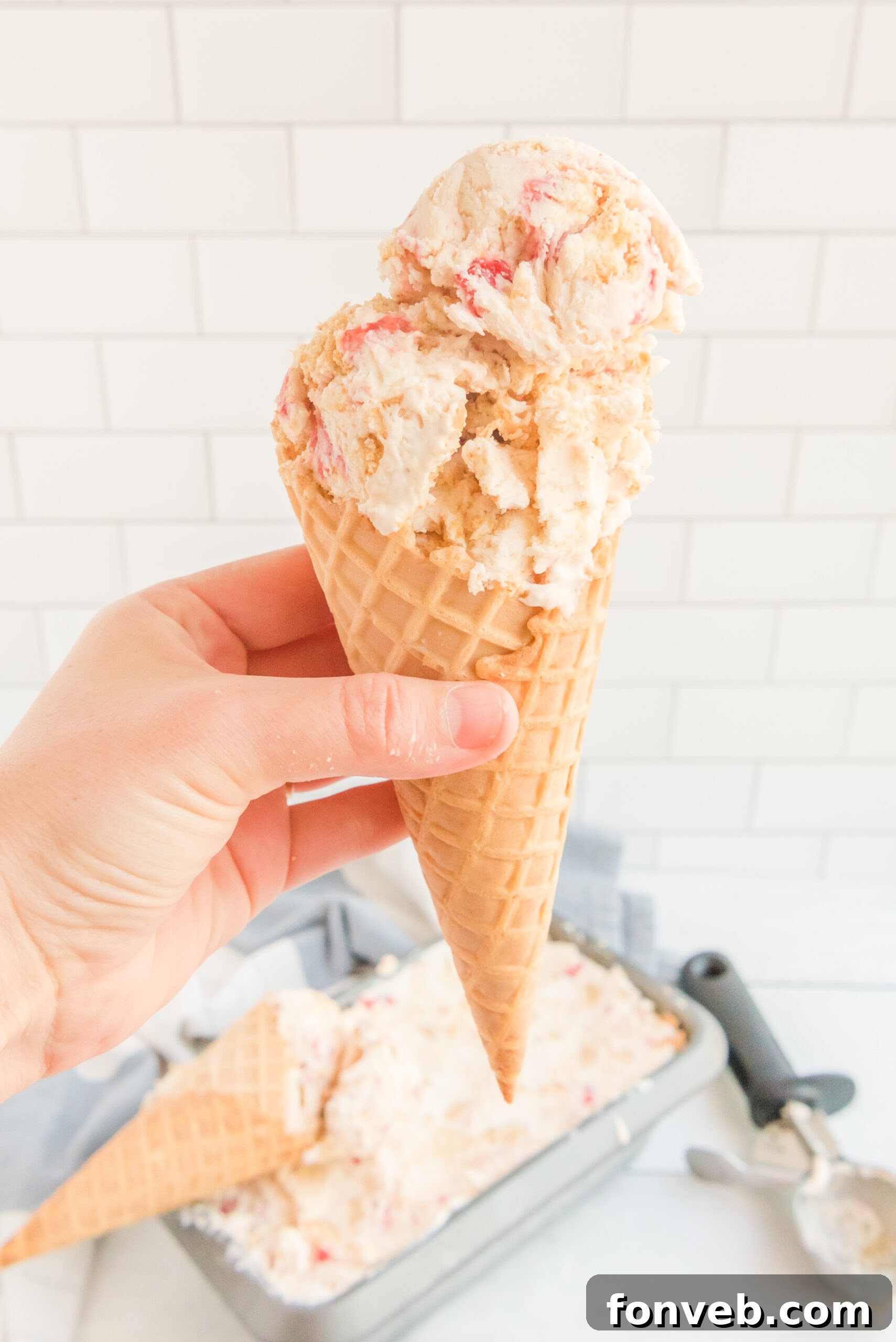 Frozen Strawberry Cheesecake Dream 8 Front view of a waffle cone with a scoop of Strawberry Cheesecake Ice Cream.