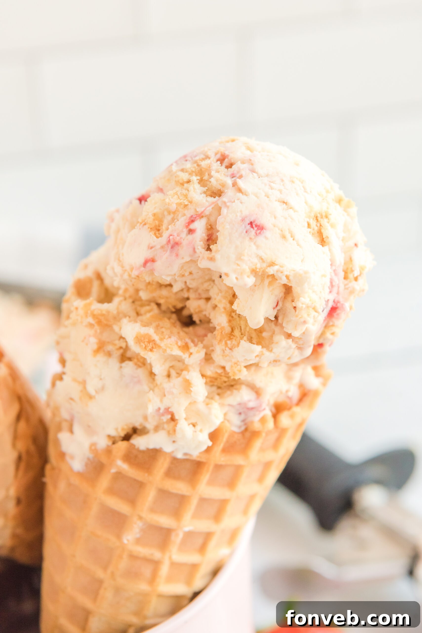 Frozen Strawberry Cheesecake Dream 10 Close up view of a waffle cone with a scoop of Strawberry Cheesecake Ice Cream.