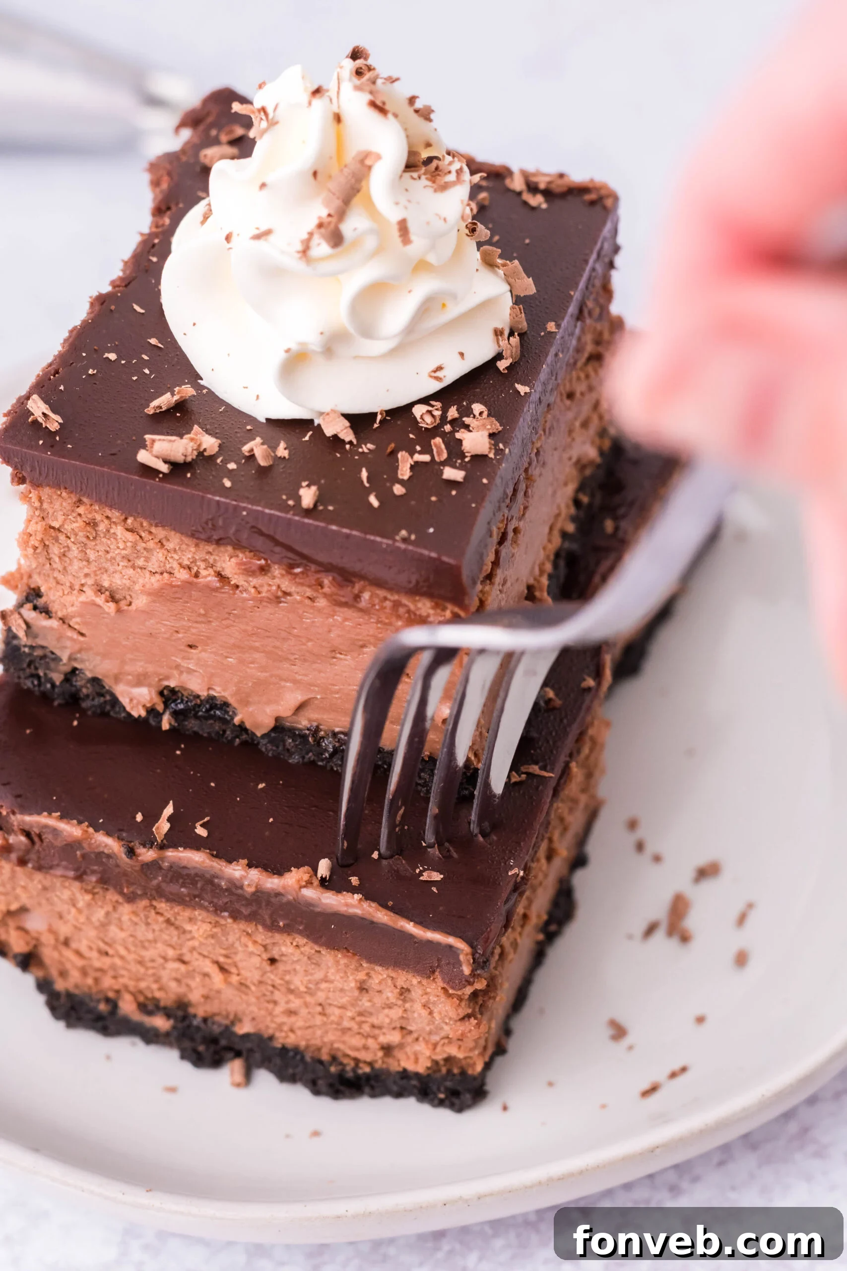 A fork removing a bite of chocolate cheesecake from one of the bars.