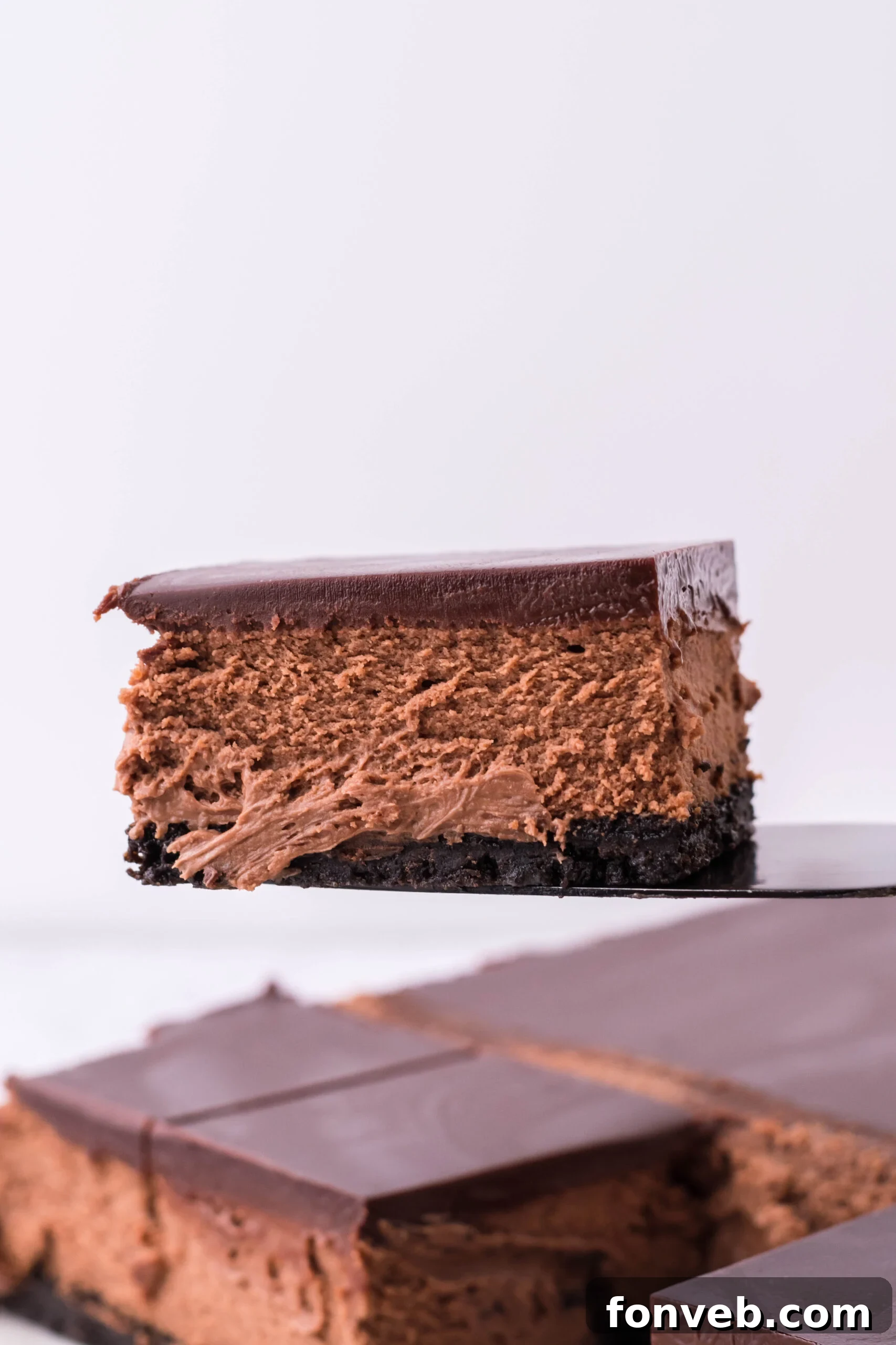 A black spatula picking up a bar of chocolate cheesecake.