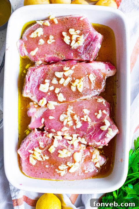 Pork chops marinating covered with foil in a baking dish.