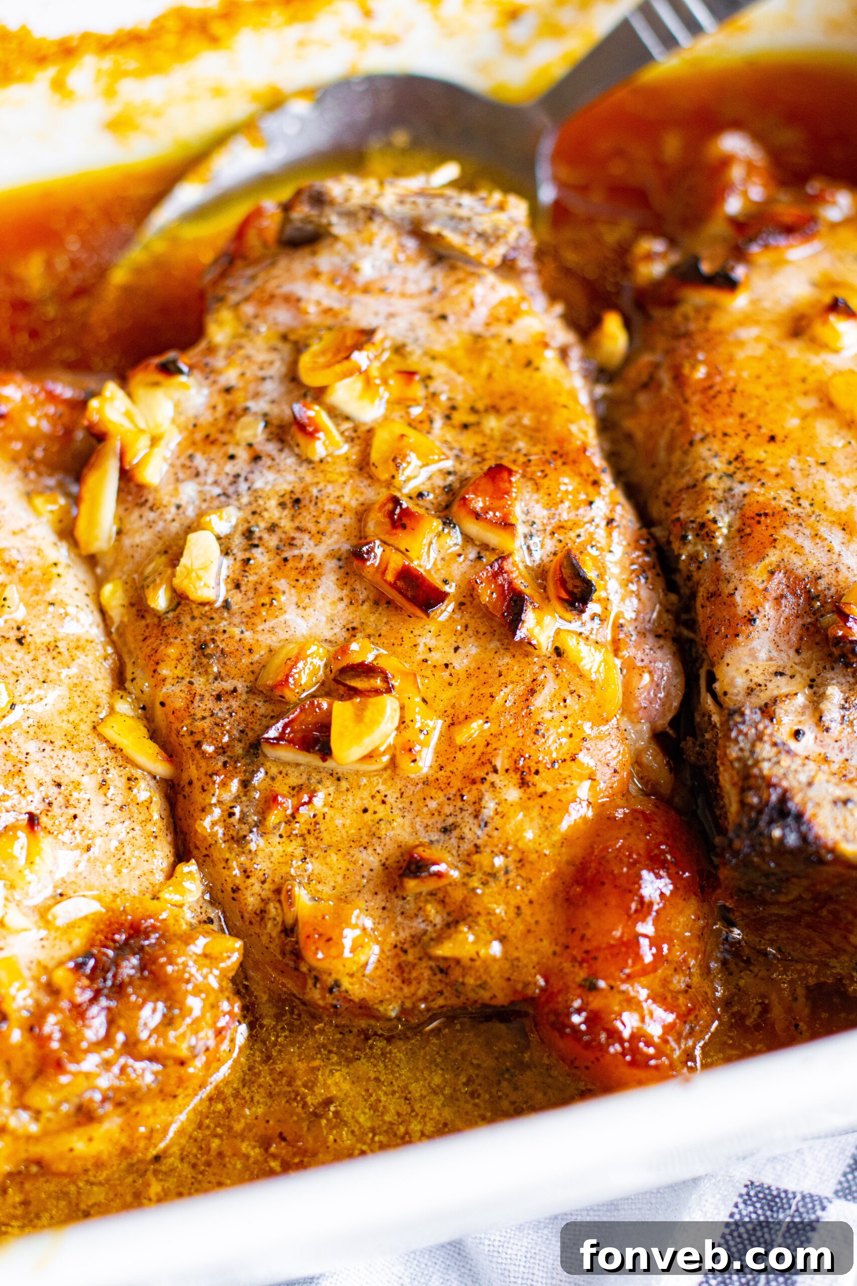 Close up view of perfectly cooked Honey Garlic Pork Chops in a white baking dish, ready to be served.
