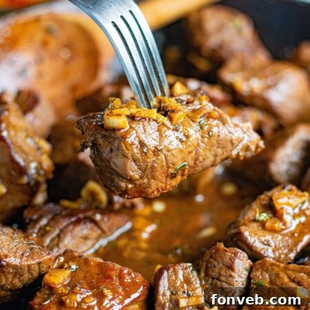 Close up view of a Garlic Honey Steak Bite on a silver fork.