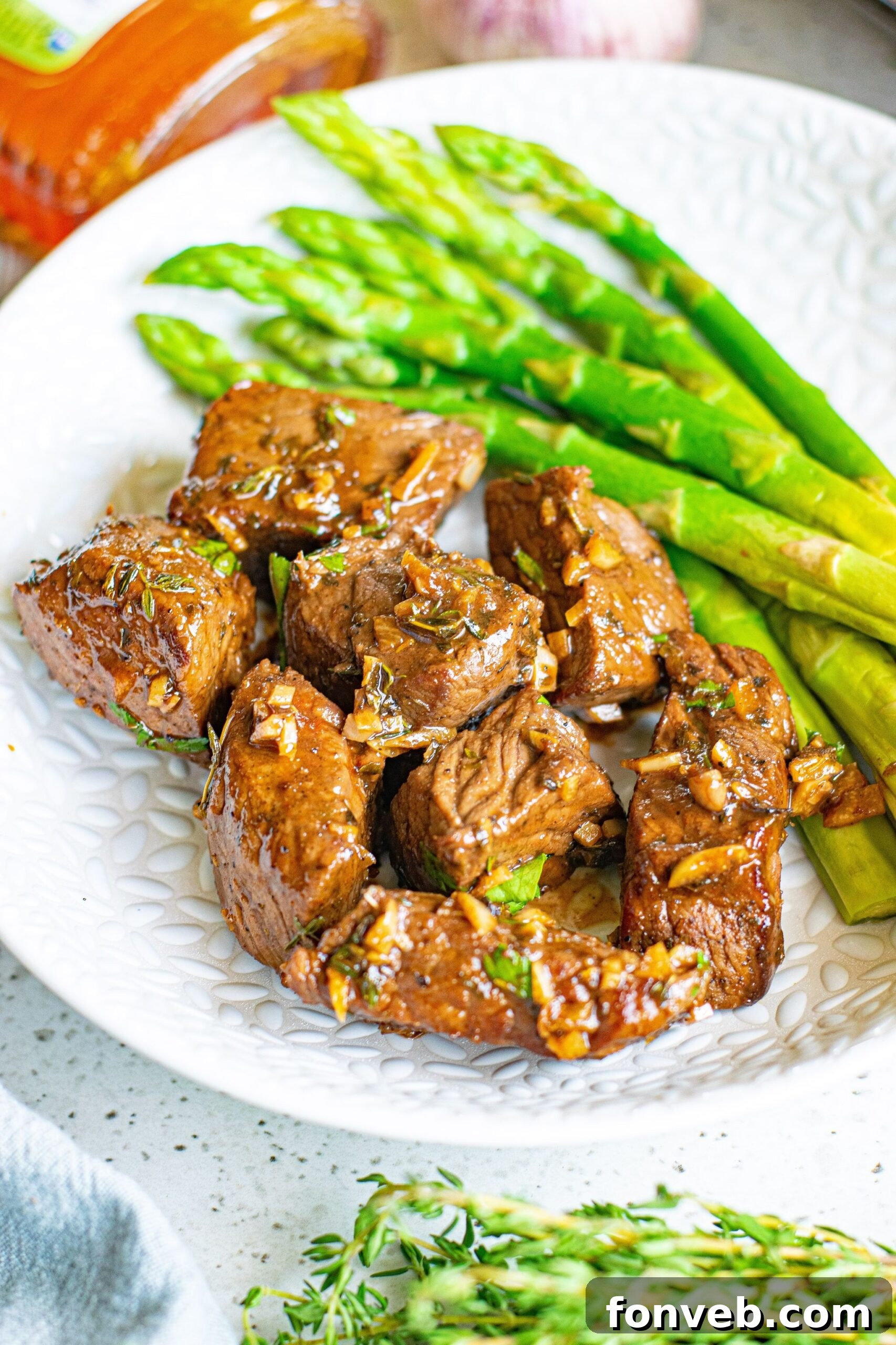 Front view of Garlic Honey Steak Bites served on a white dish with asparagus.