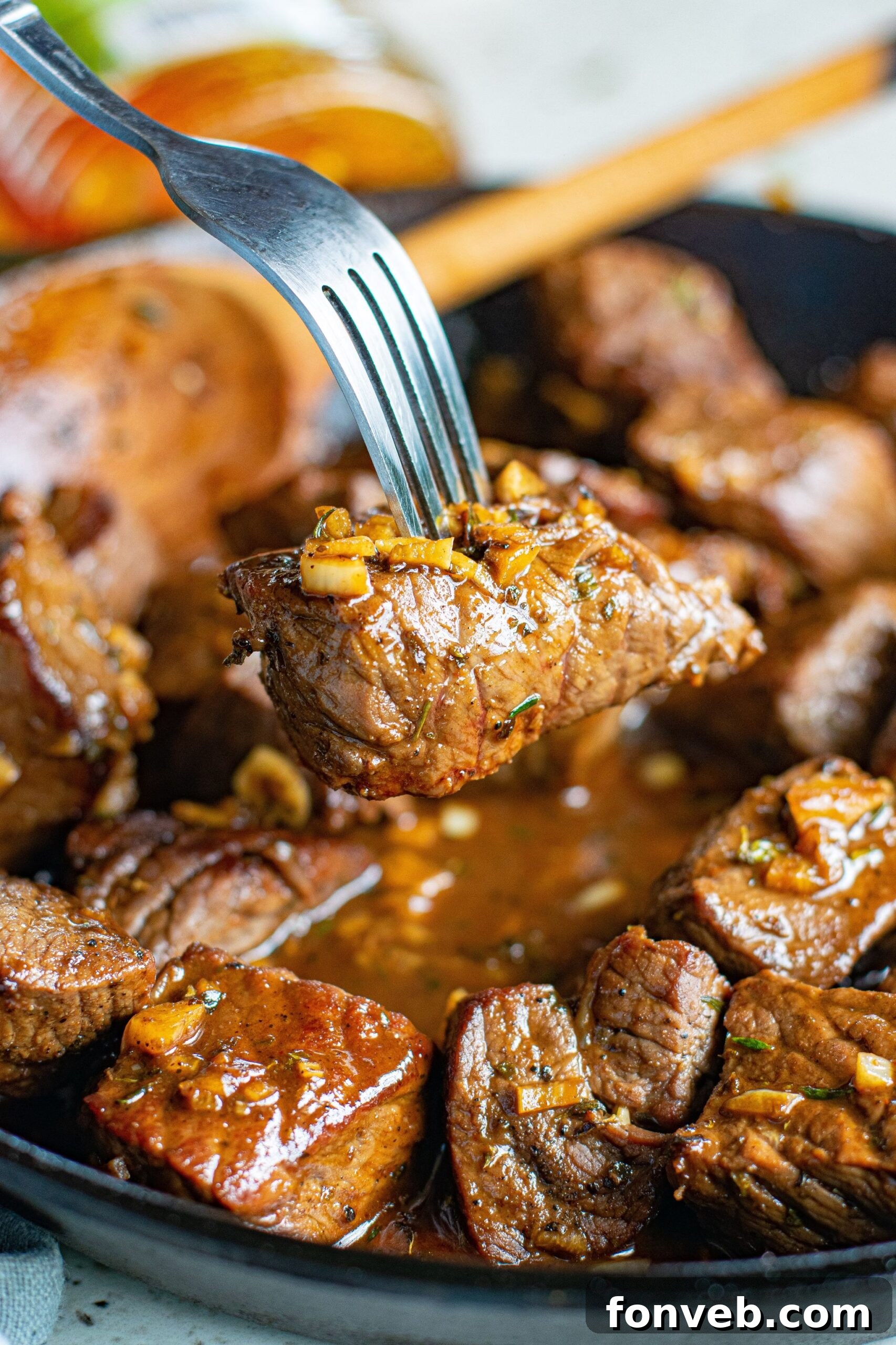 Close up view of a Garlic Honey Steak Bite on a silver fork.