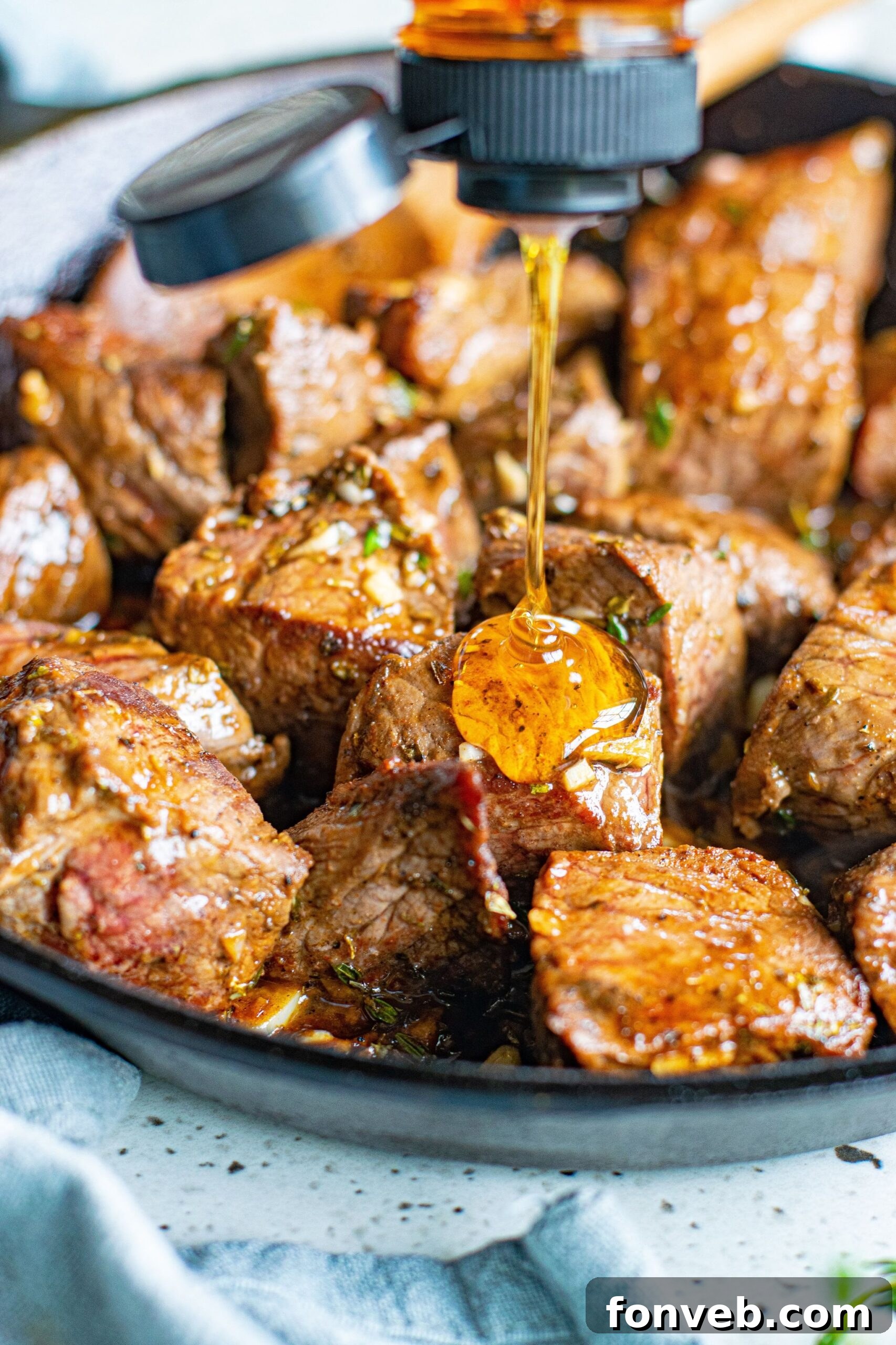Close up view of honey being drizzled onto Garlic Honey Steak Bites.