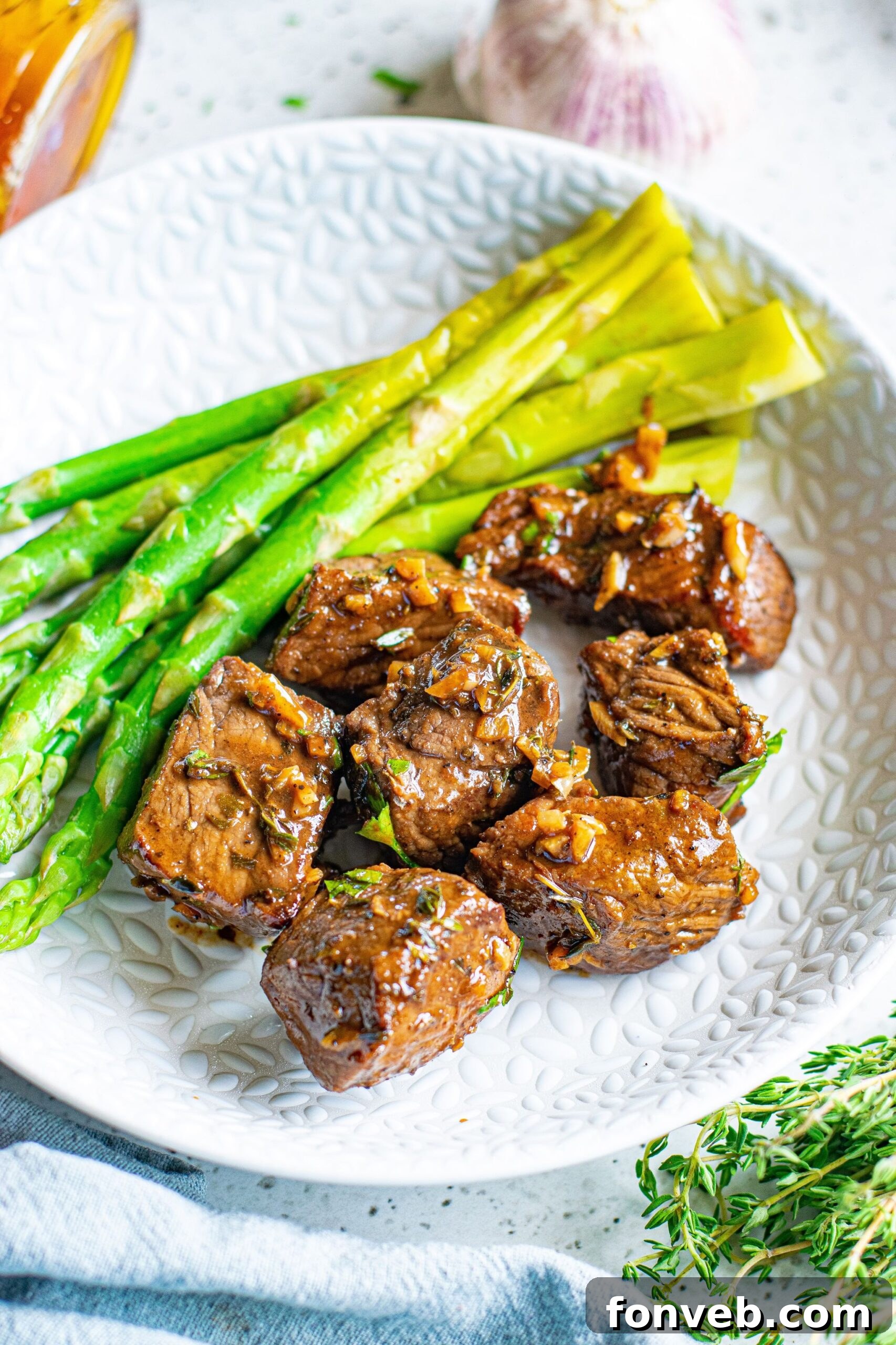 Front view of Garlic Honey Steak Bites served on a white dish with asparagus.