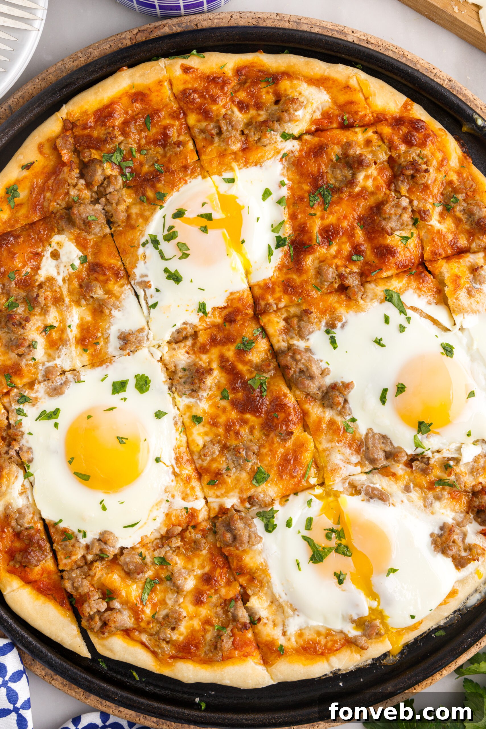 A freshly sliced Breakfast Pizza on a black pizza dish, showcasing its square portions and appealing toppings.