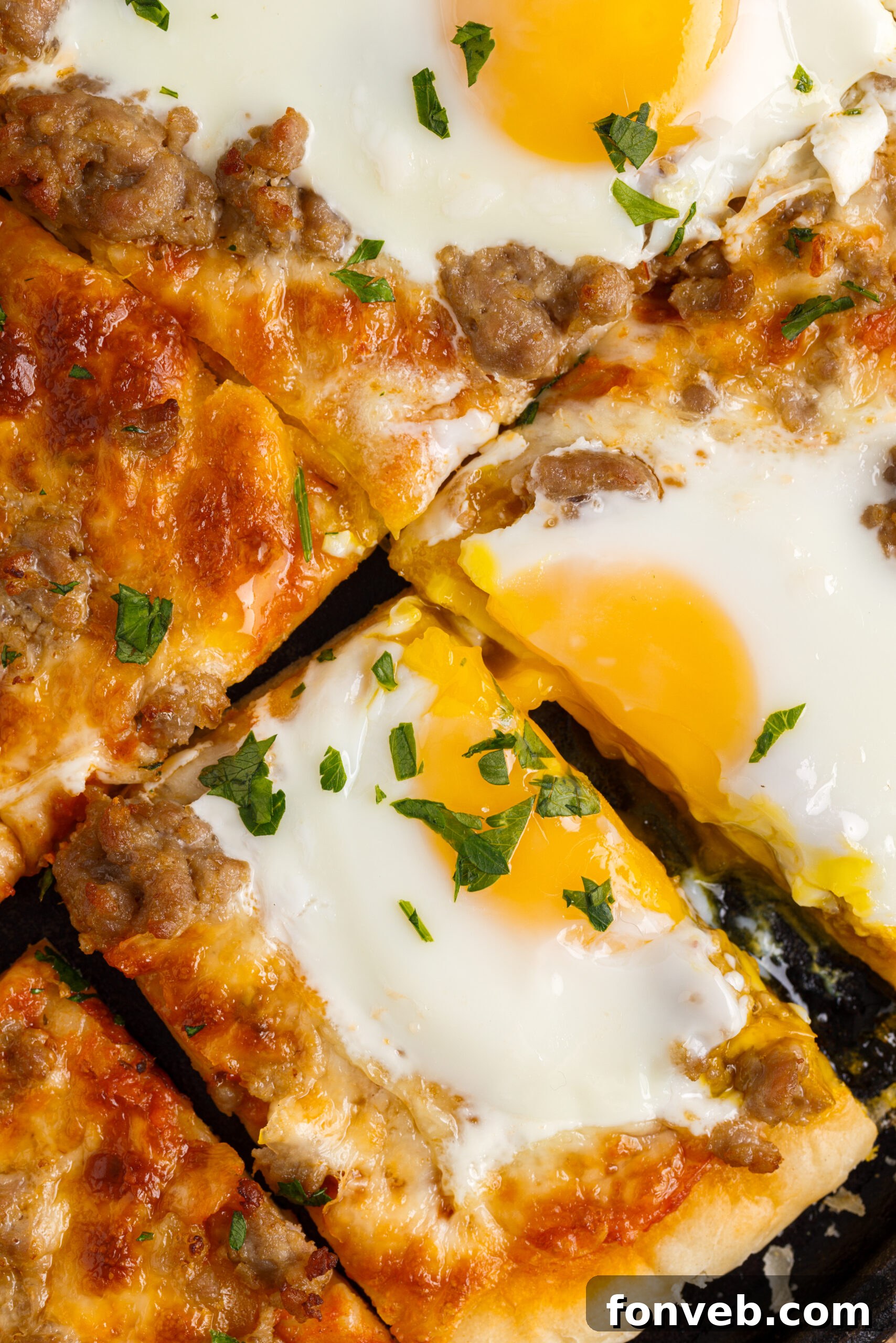 A close-up view of a perfectly cut slice of Breakfast Pizza on a black pizza dish, highlighting the individual square portions.