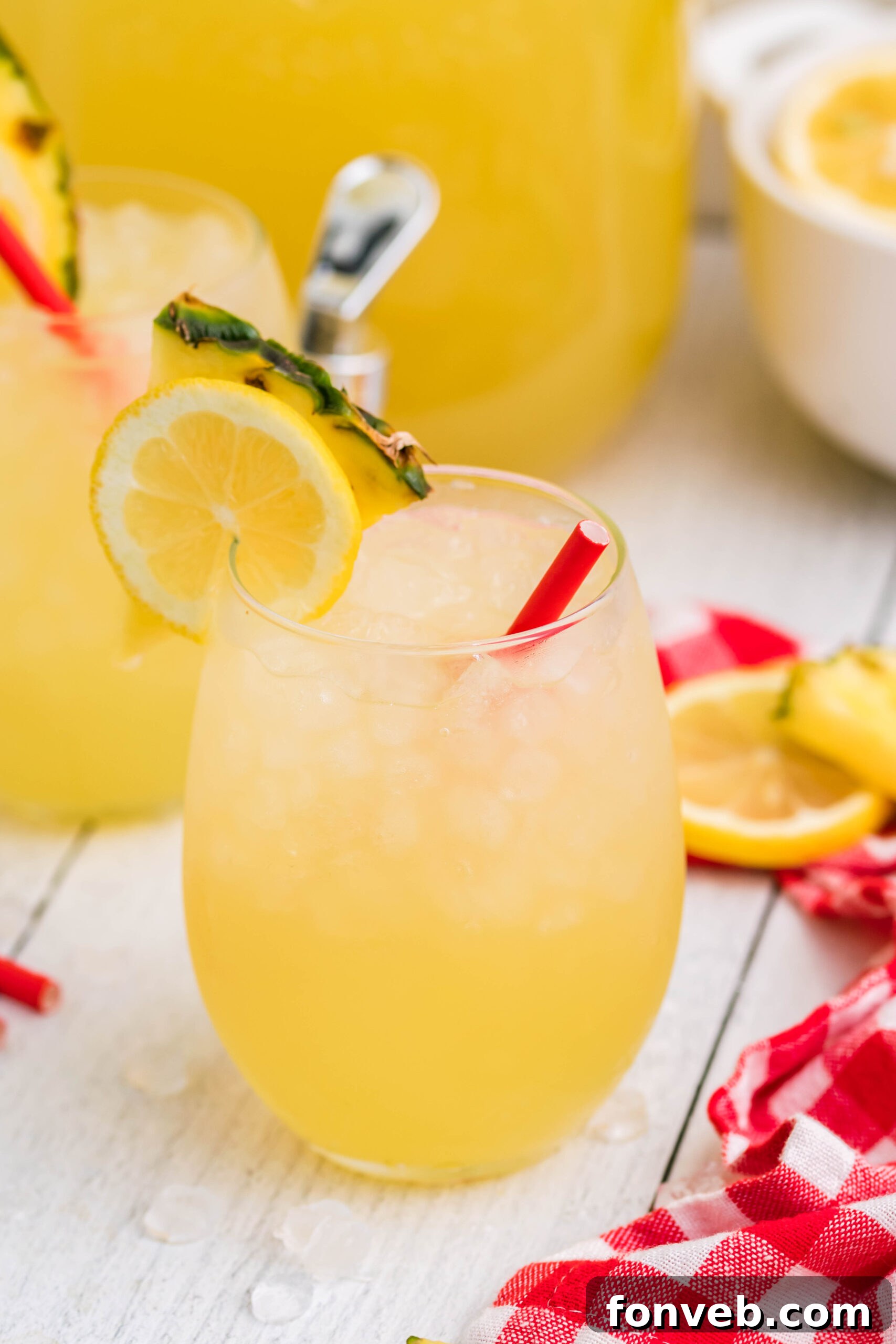 Front view of two glasses of Pineapple Vodka Lemonade garnished with a lemon and pineapple slice, showcasing the refreshing blend.