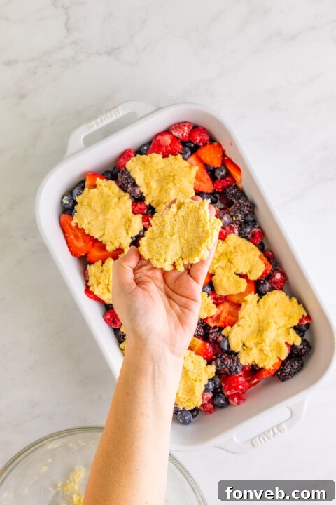The cobbler baking in the oven, with the topping beginning to brown and the filling starting to bubble.