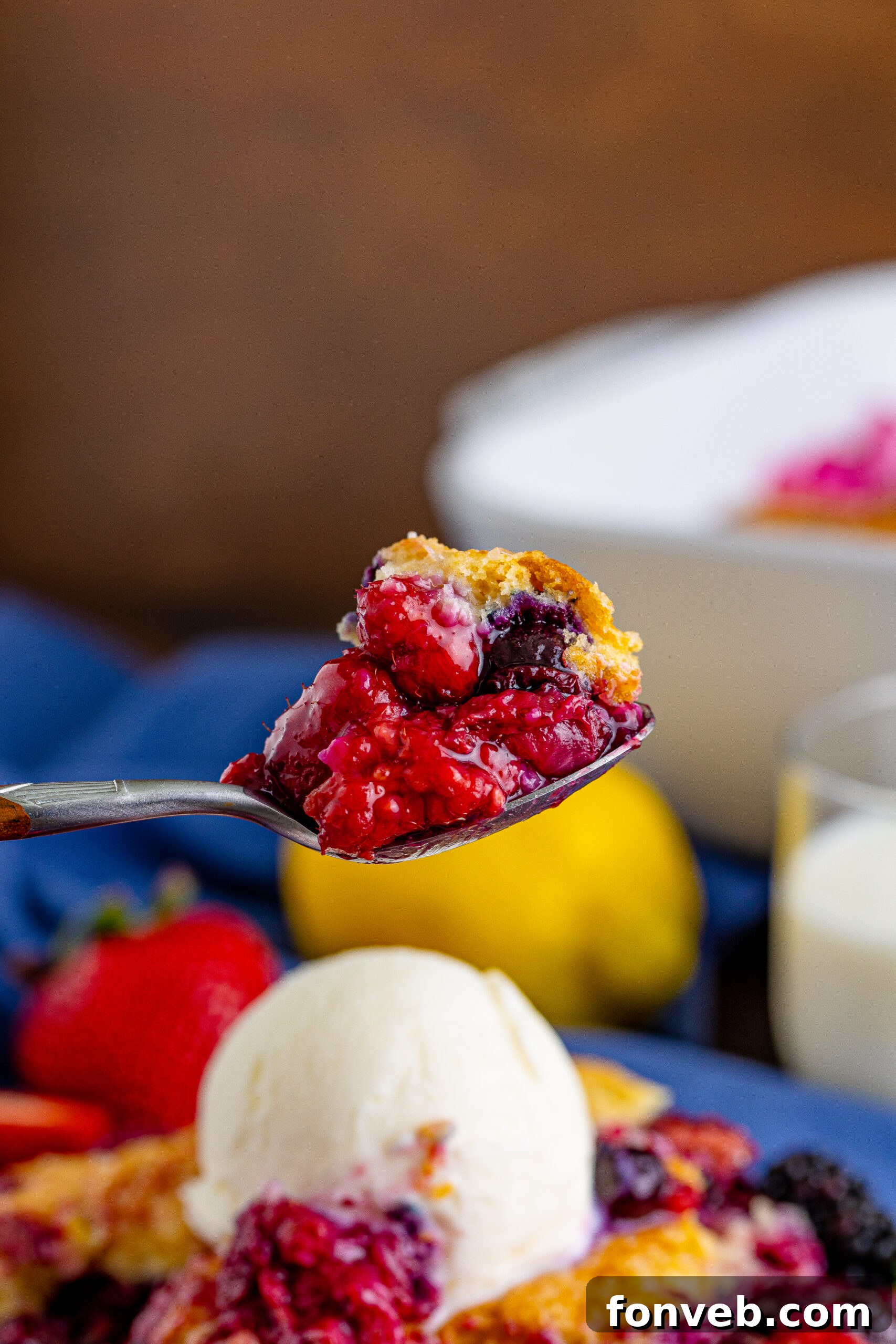 Close-up front view of a perfect bite of Mixed Berry Cobbler on a silver spoon, ready to be enjoyed.