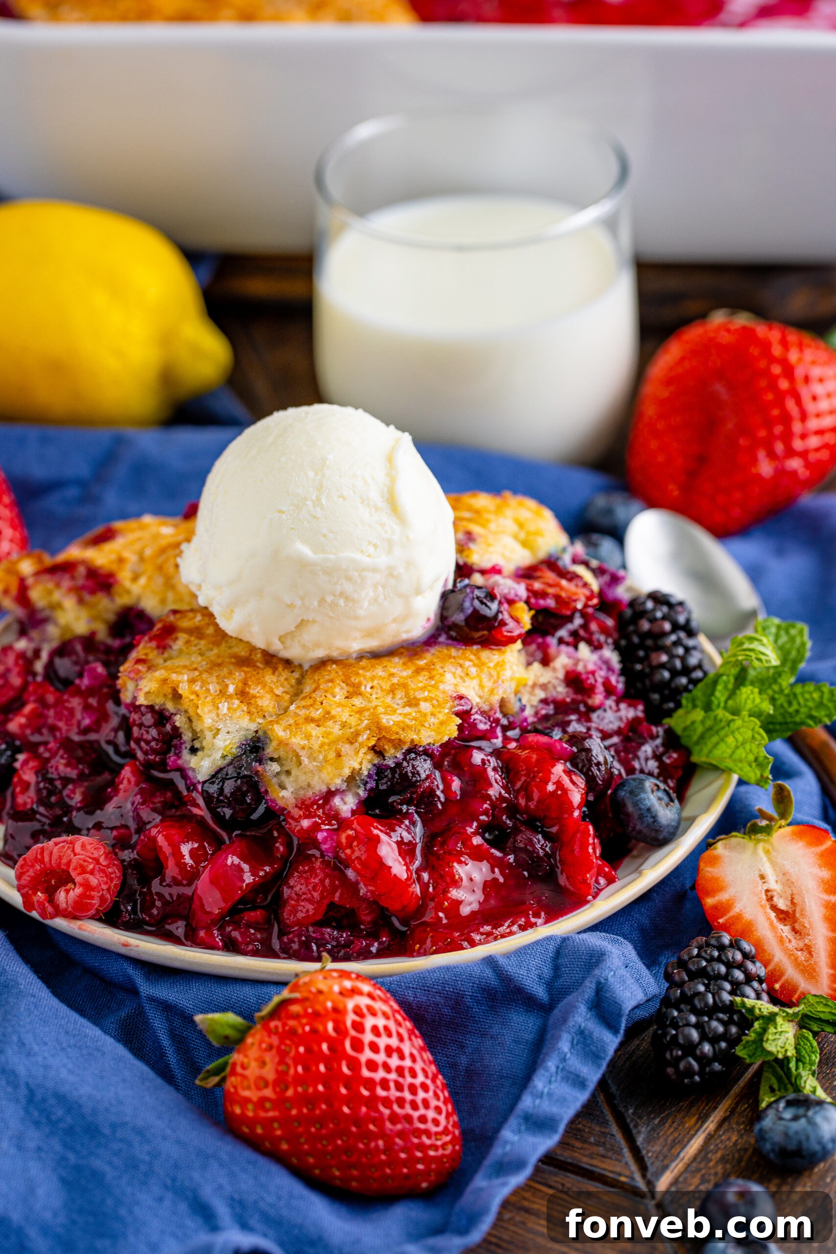 Front view of a vibrant Mixed Berry Cobbler in a white baking dish, showcasing the various colors of berries and the golden biscuit topping.