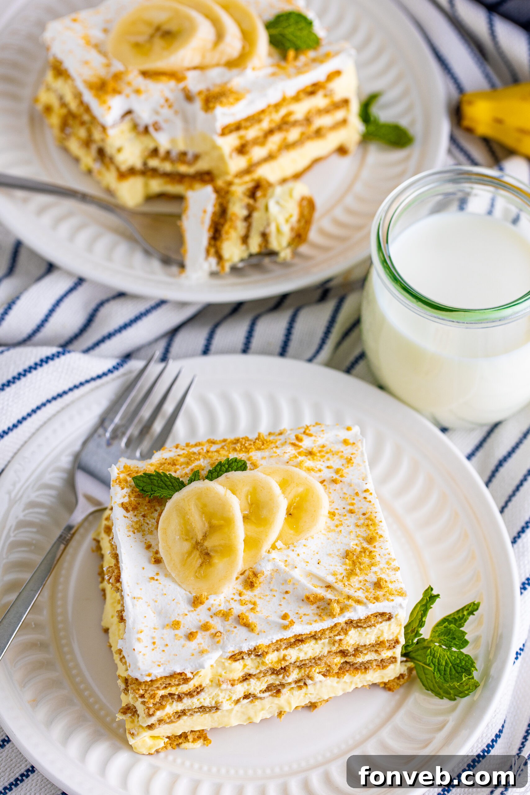 An inviting overhead view of a slice of Banana Icebox Cake on a white plate, showcasing its beautiful layers and creamy texture, garnished with fresh banana.