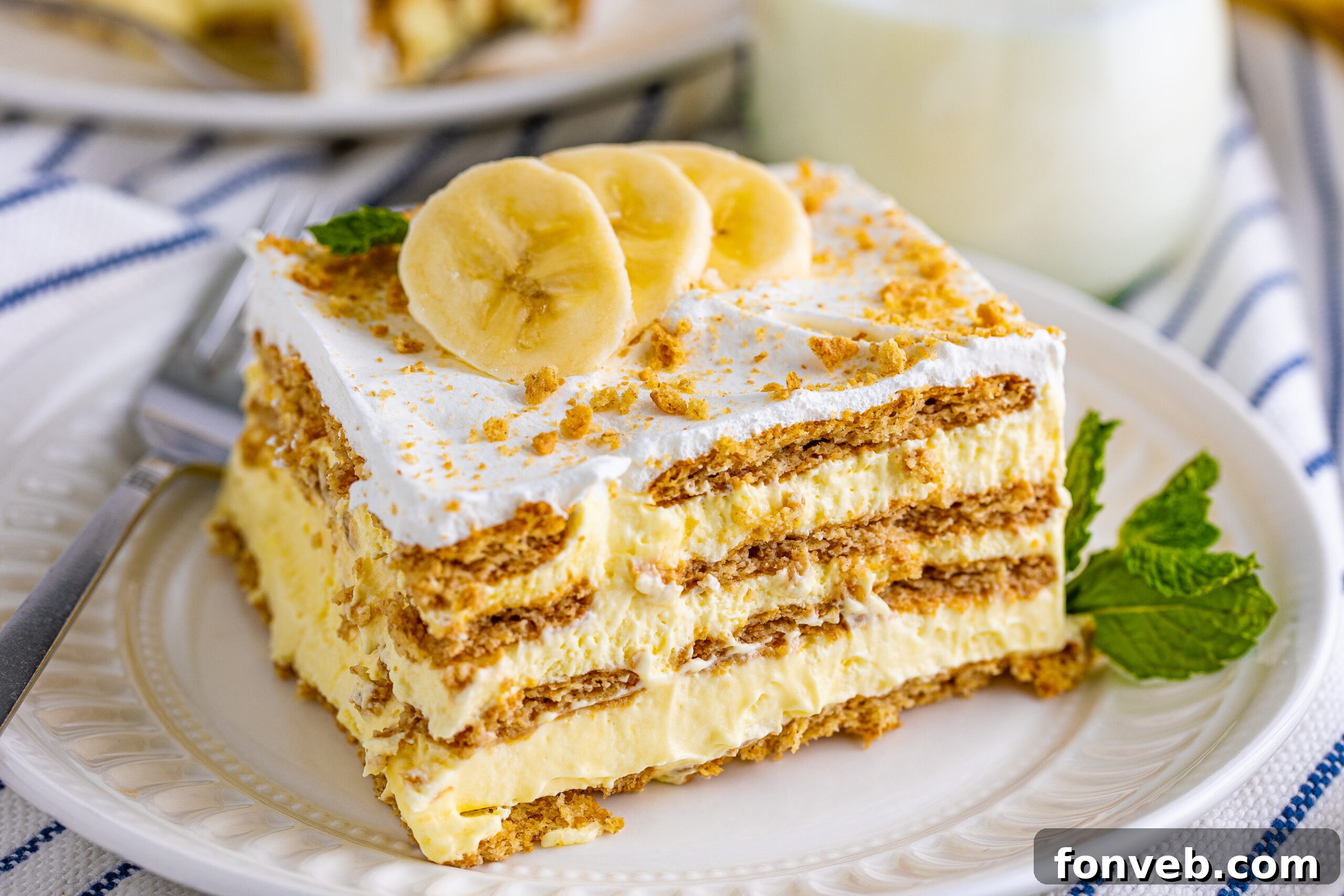 A wide overhead shot of a luscious No-Bake Banana Icebox Cake, beautifully presented on a white plate and adorned with fresh banana slices on top.