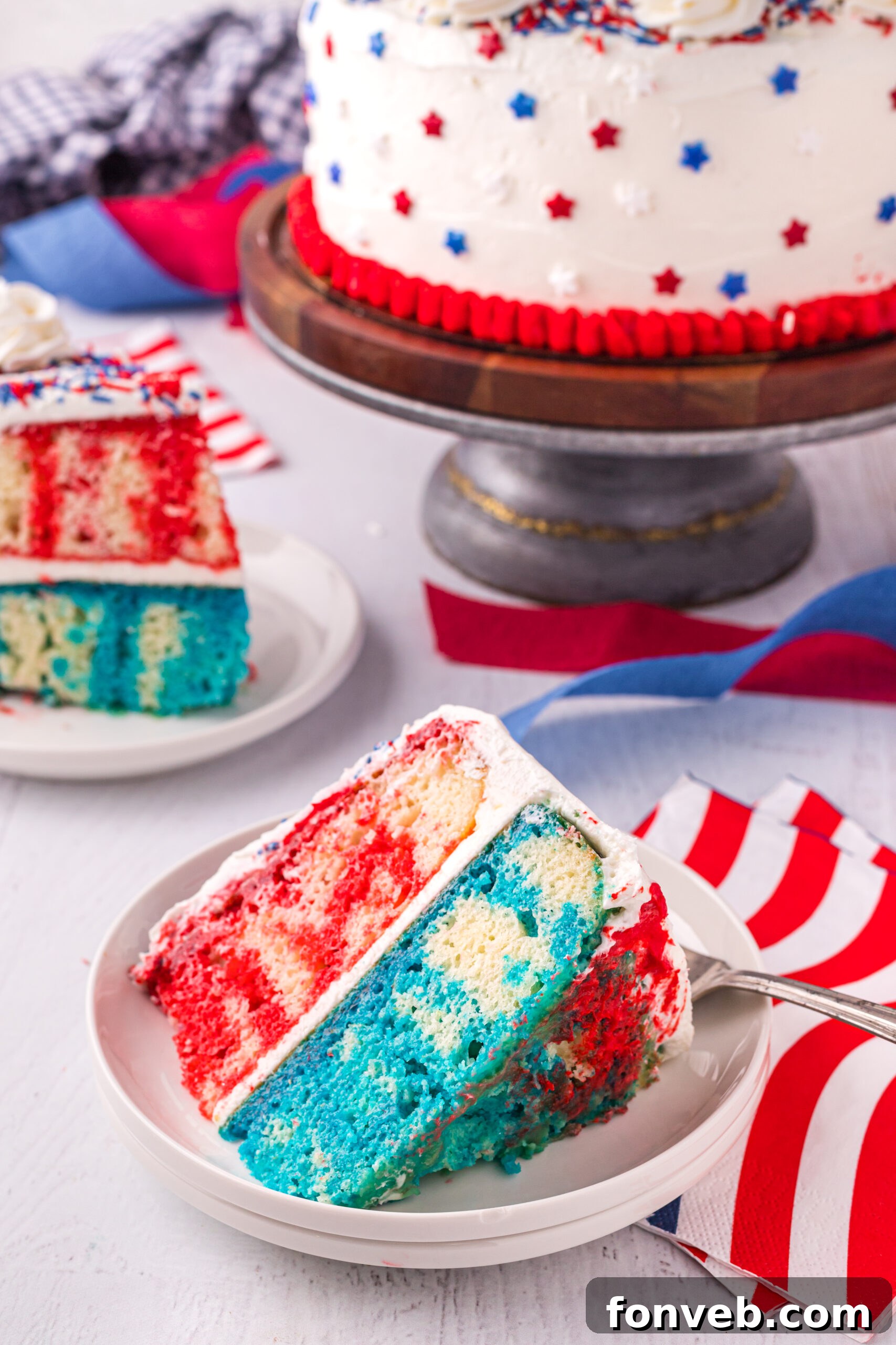 Front view of a slice of 4th of July Cake on a white plate, showcasing the distinct red and blue Jell-O layers.