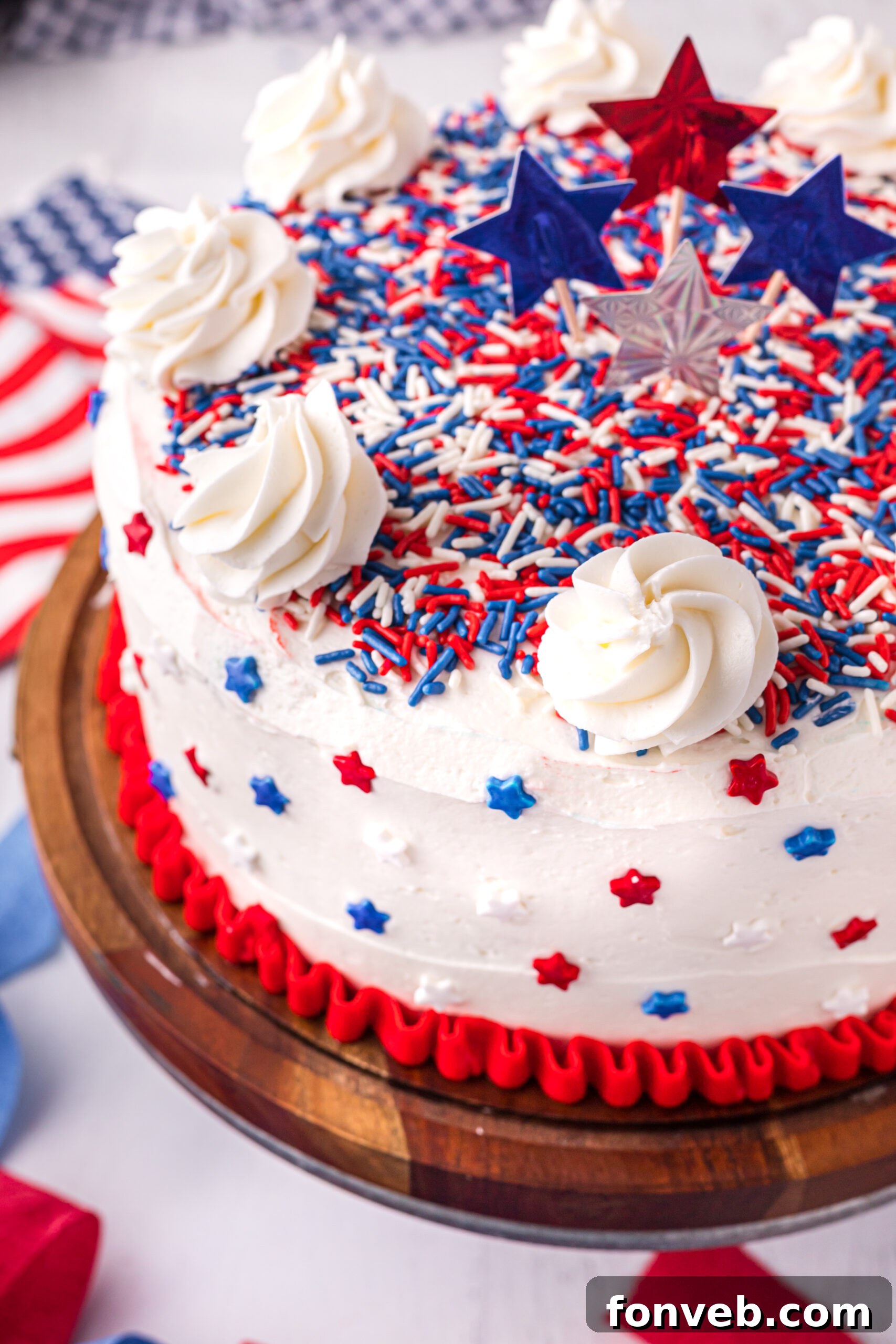 Close up view of the layered and frosted 4th of July Cake on a wooden cake stand, highlighting its festive appeal.