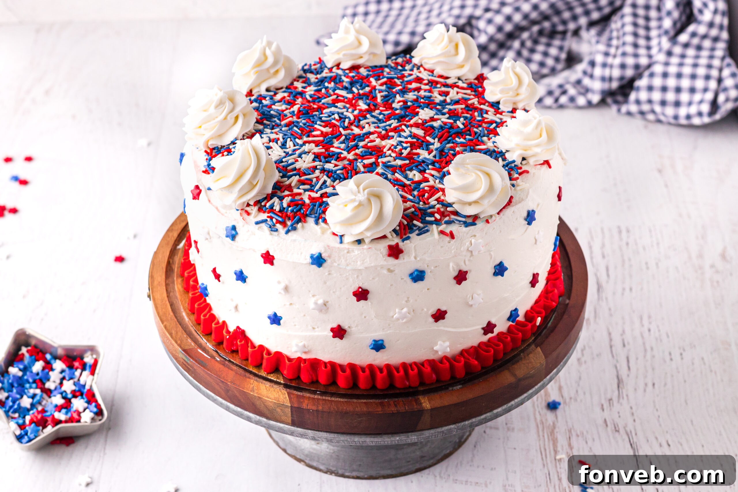 Front view of the fully decorated 4th of July Cake on a wooden cake stand, showcasing its patriotic design.