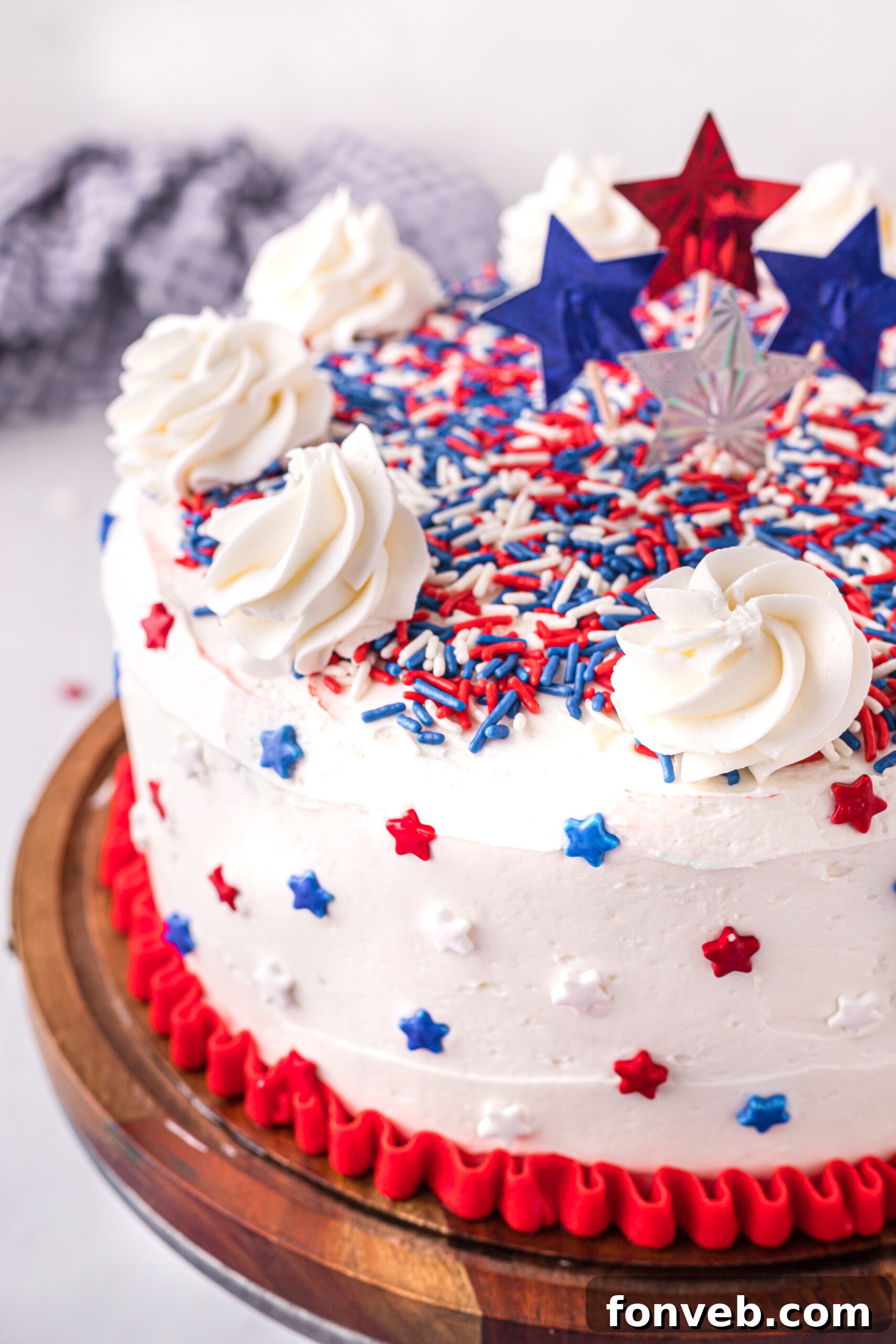 Close up view of the layered 4th of July Cake on a wooden cake stand, highlighting the festive Jell-O infusions.