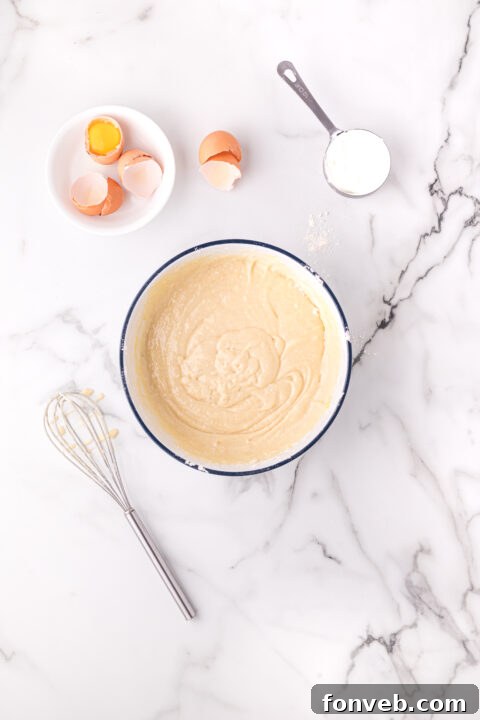 Close-up of cake batter being poured into a round baking pan.