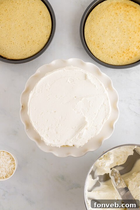 Tropical Coconut Dream Cake 15 Finished Coconut Layer Cake being decorated with swirls of frosting on top.
