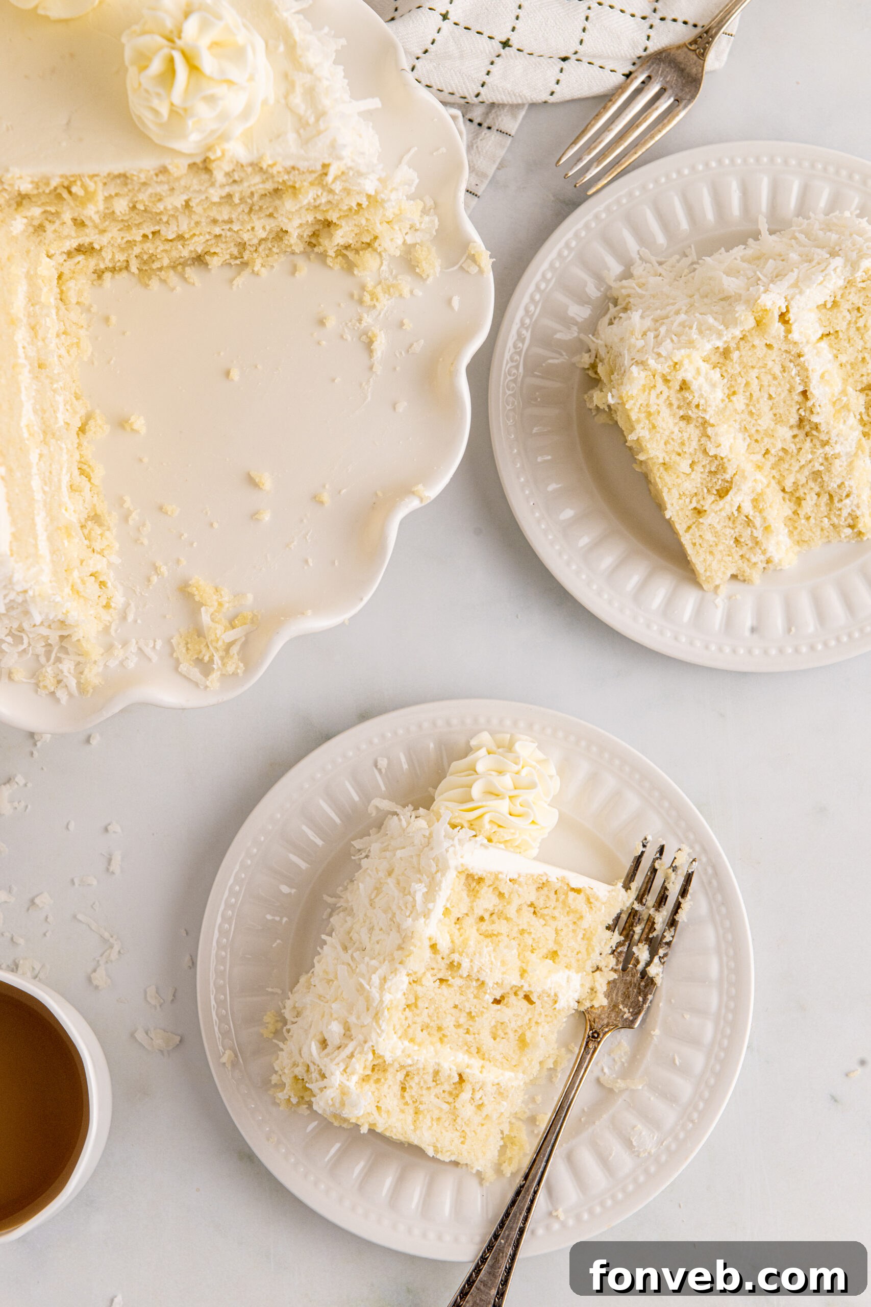 Tropical Coconut Dream Cake 17 An overhead shot of a slice of Coconut Layer Cake on a white plate, with a silver fork having taken a bite, highlighting its tempting layers and fluffy frosting.