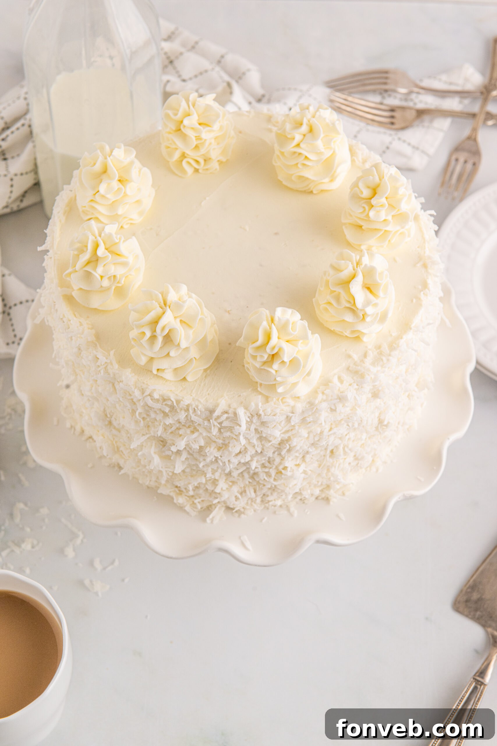 Tropical Coconut Dream Cake 4 Overhead view of the decadent Coconut Layer Cake on a white cake stand, showcasing its intricate frosting design.