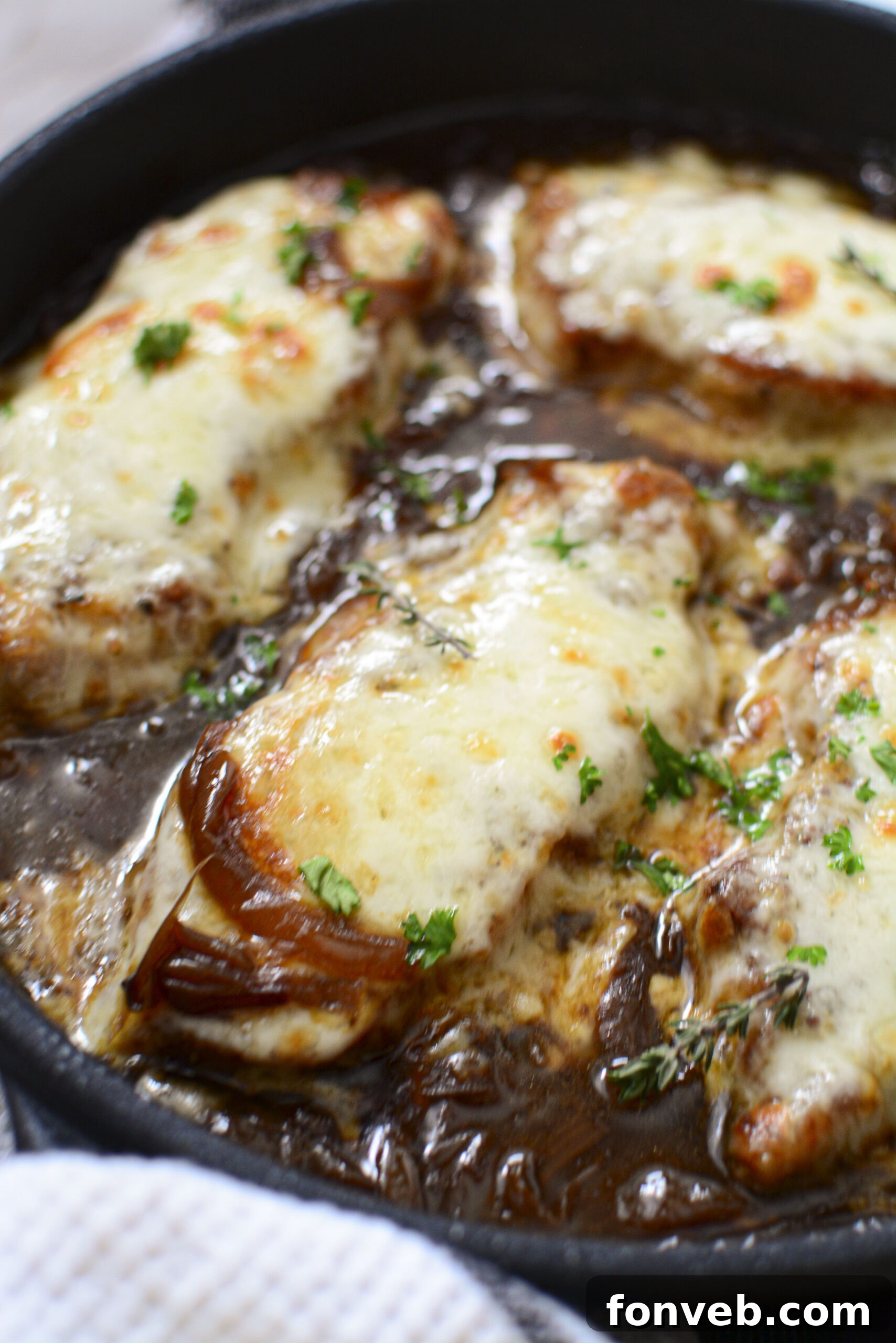 Another enticing close-up of French Onion Pork Chops, showing the melted cheese topping the onions and pork in the skillet.