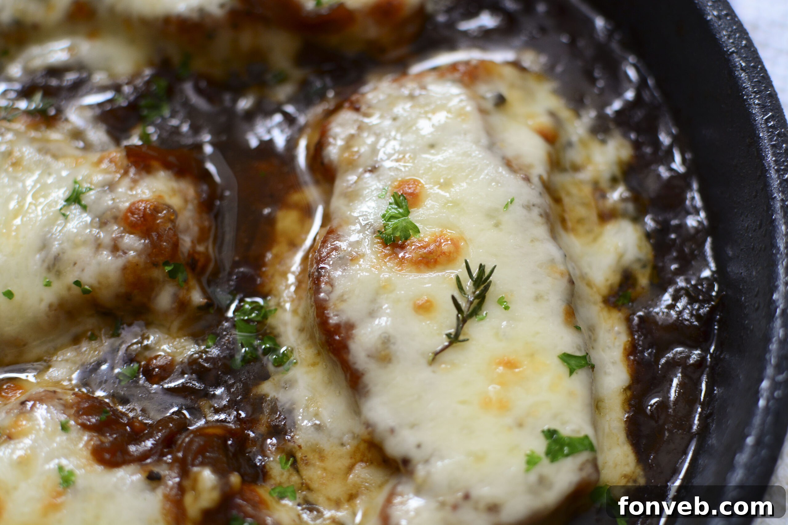 Overhead view of French Onion Pork Chops simmering in a cast iron skillet, showcasing the rich onion gravy.
