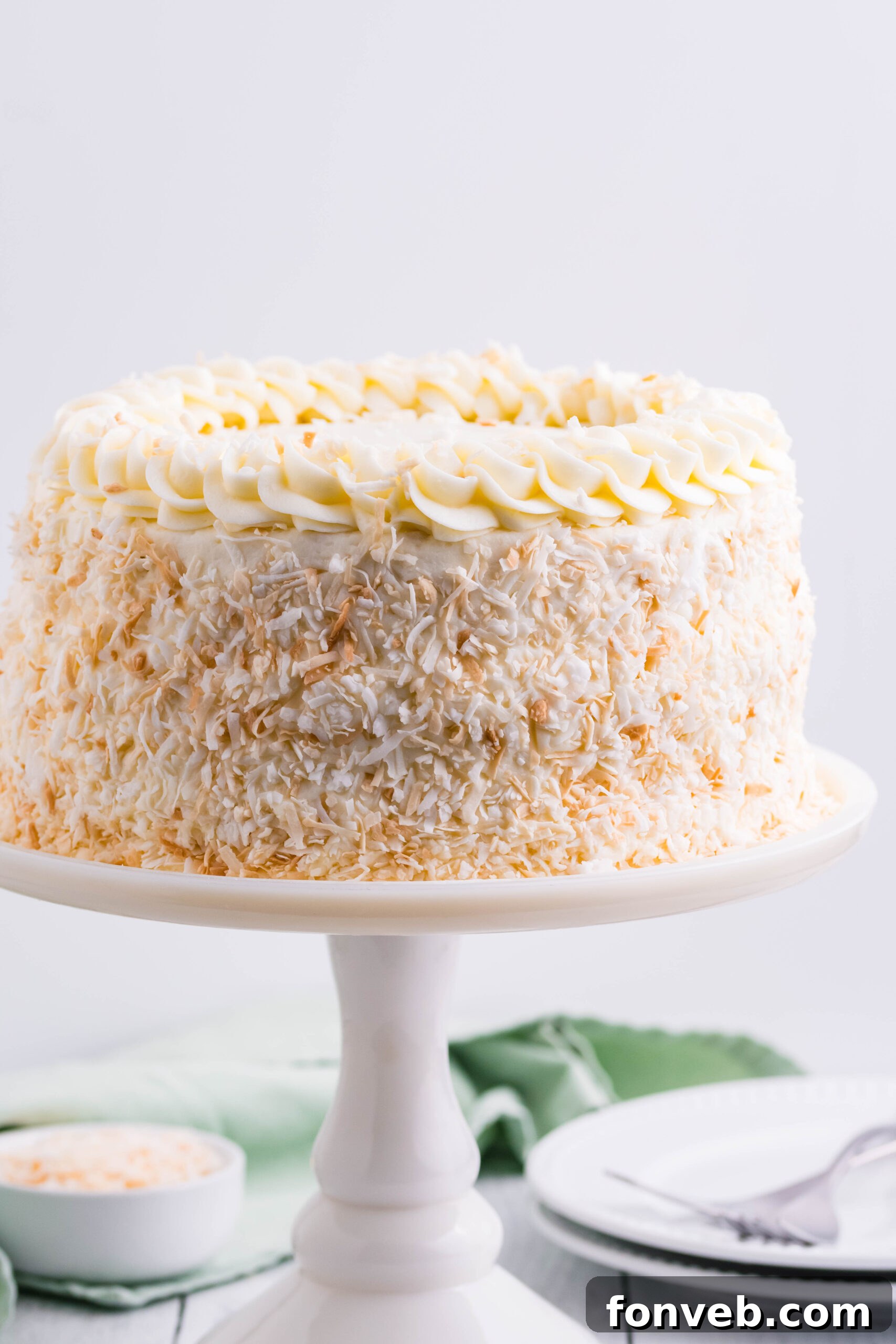 Front view of Coconut Custard Cake on a white cake stand.
