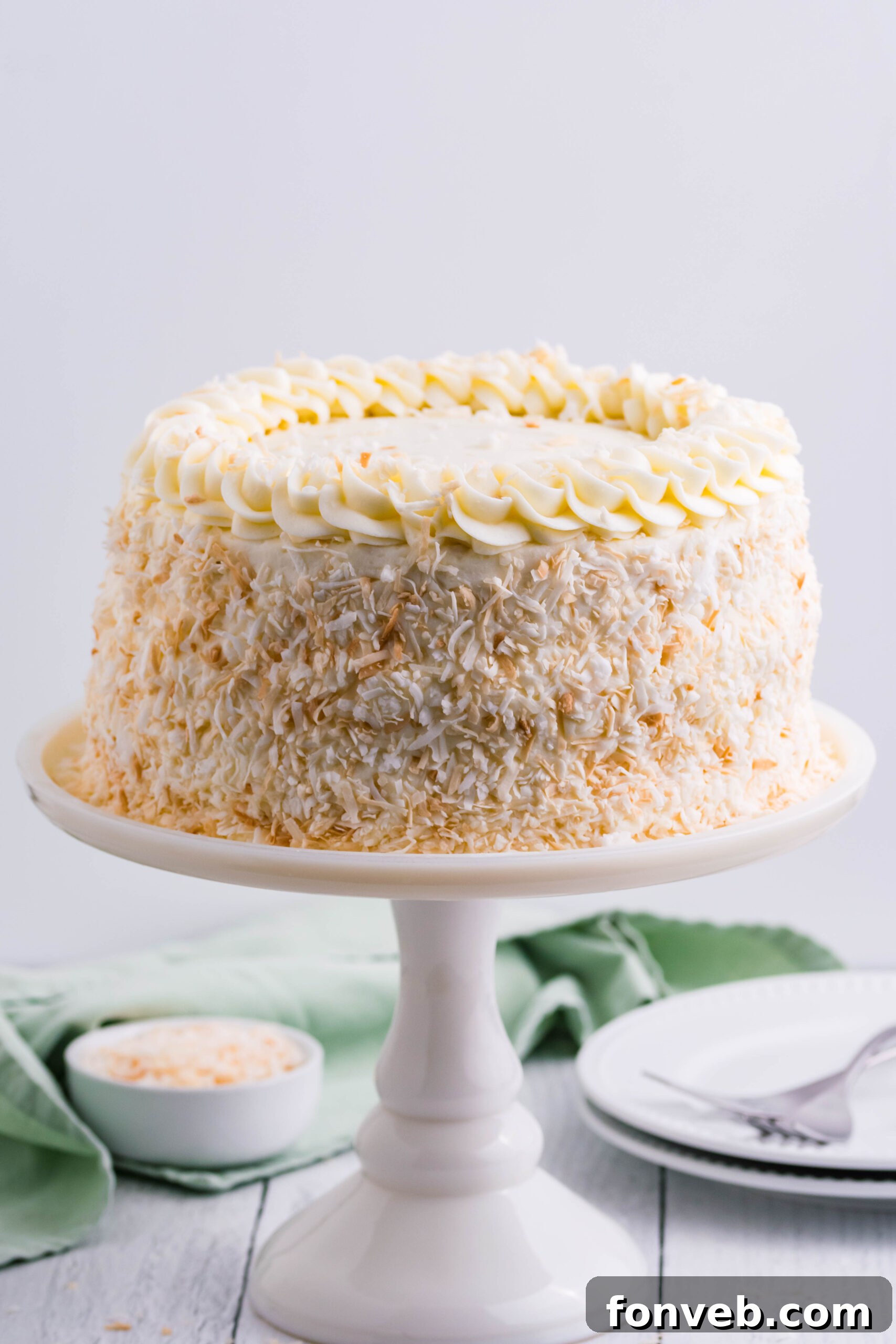 Front view of Coconut Custard Cake on a white cake stand.