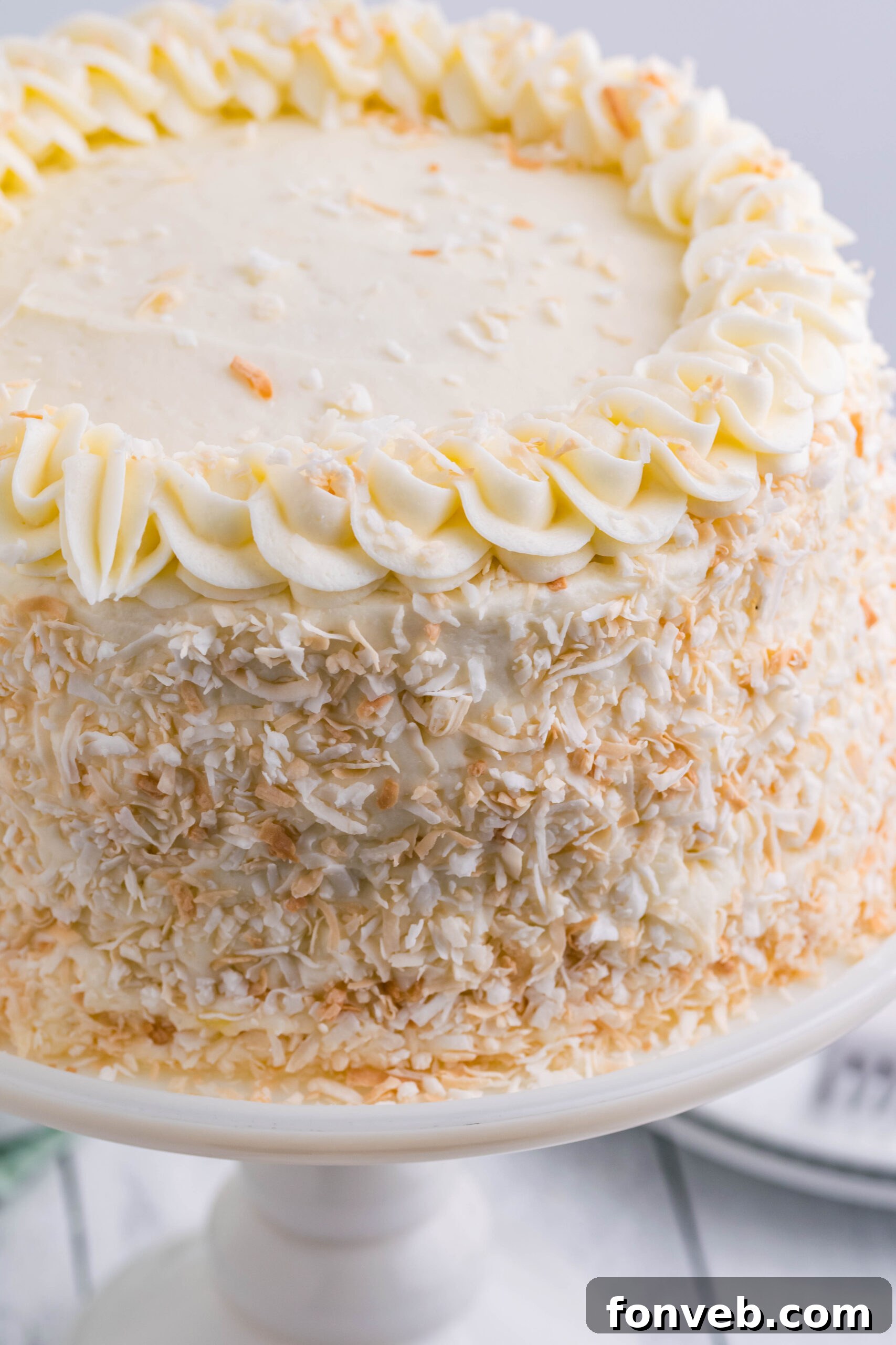 Close up view of Coconut Custard Cake on a white cake stand.