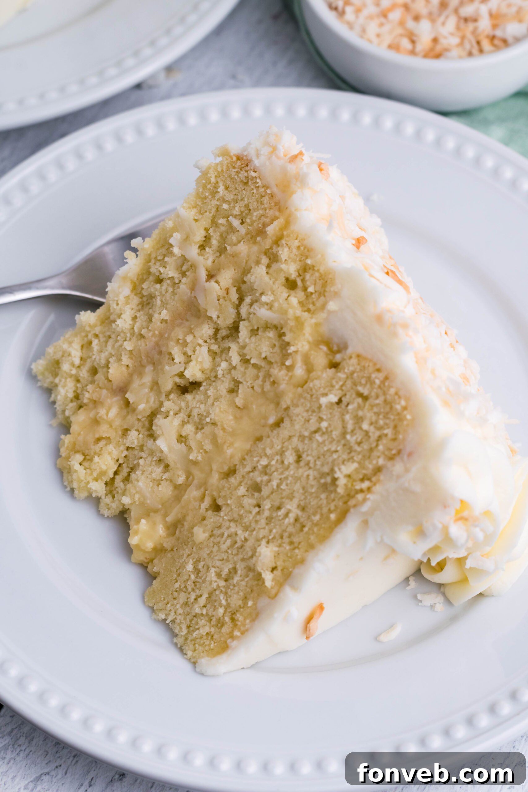Close up view of a slice of Coconut Custard Cake on a white plate.