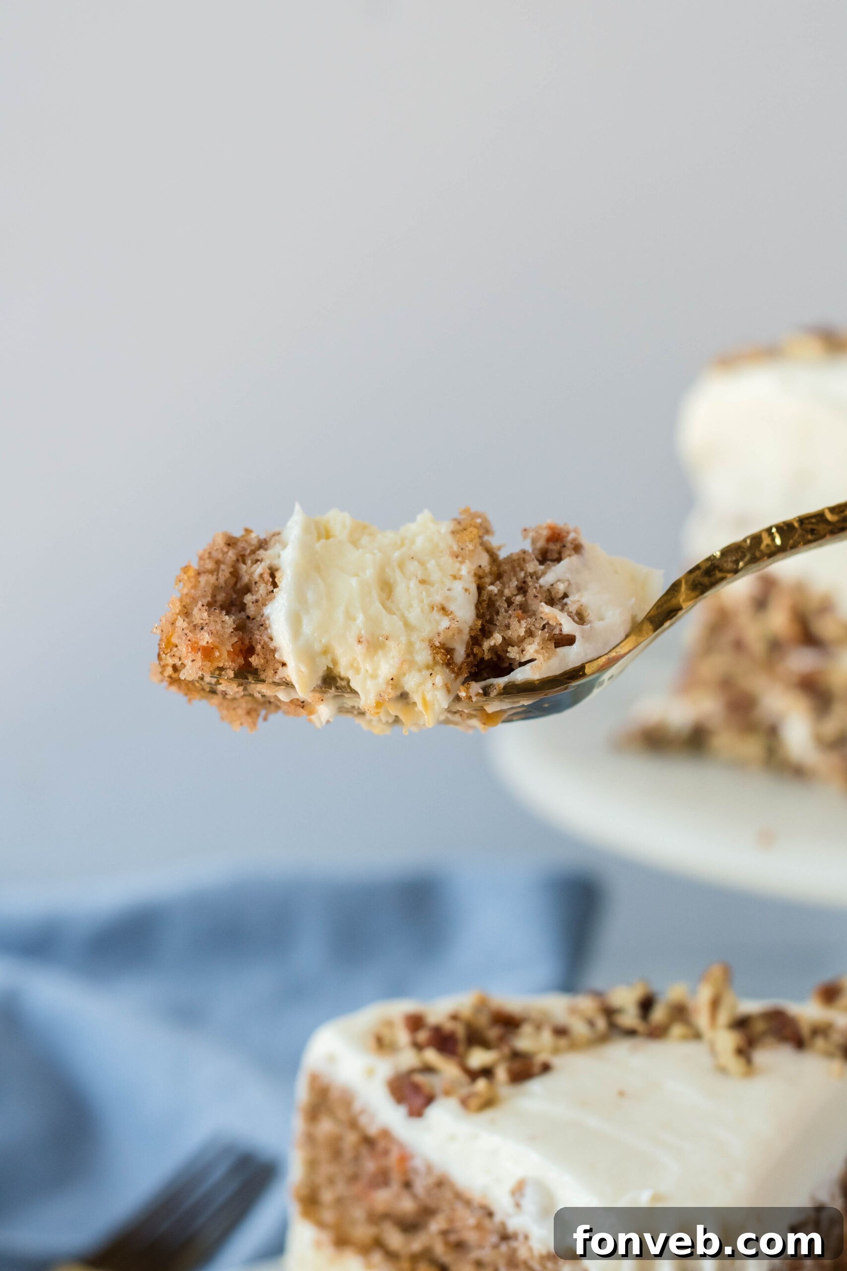 Side view of a bite of Carrot Cake Cheesecake on a gold fork.
