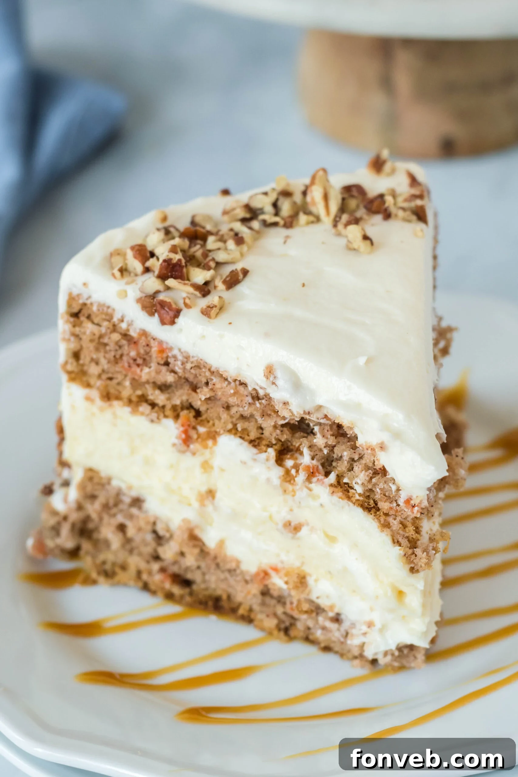 Front view of a slice of Carrot Cake Cheesecake on a white plate drizzled with caramel.