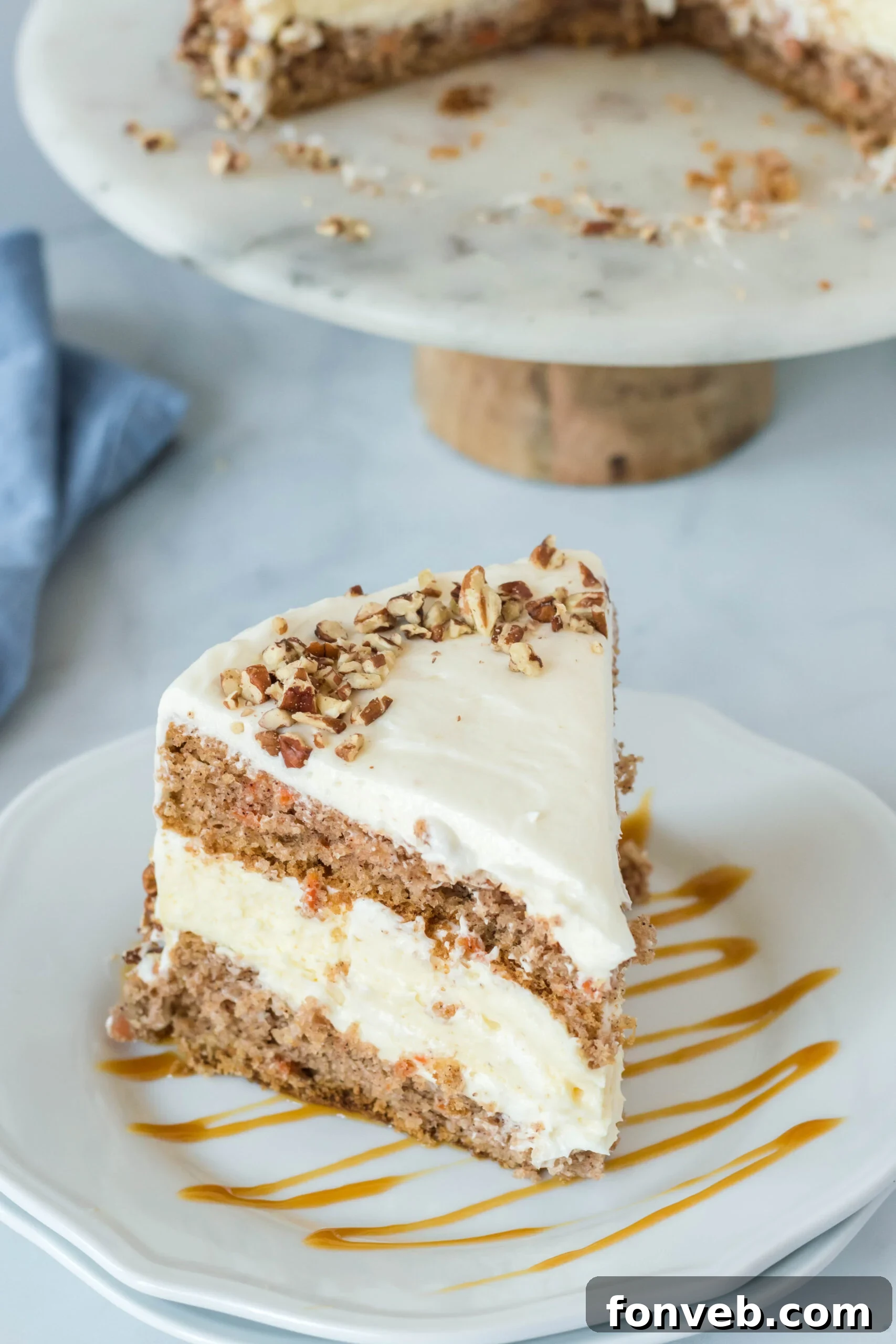 Front view of a slice of Carrot Cake Cheesecake on a white plate drizzled with caramel.