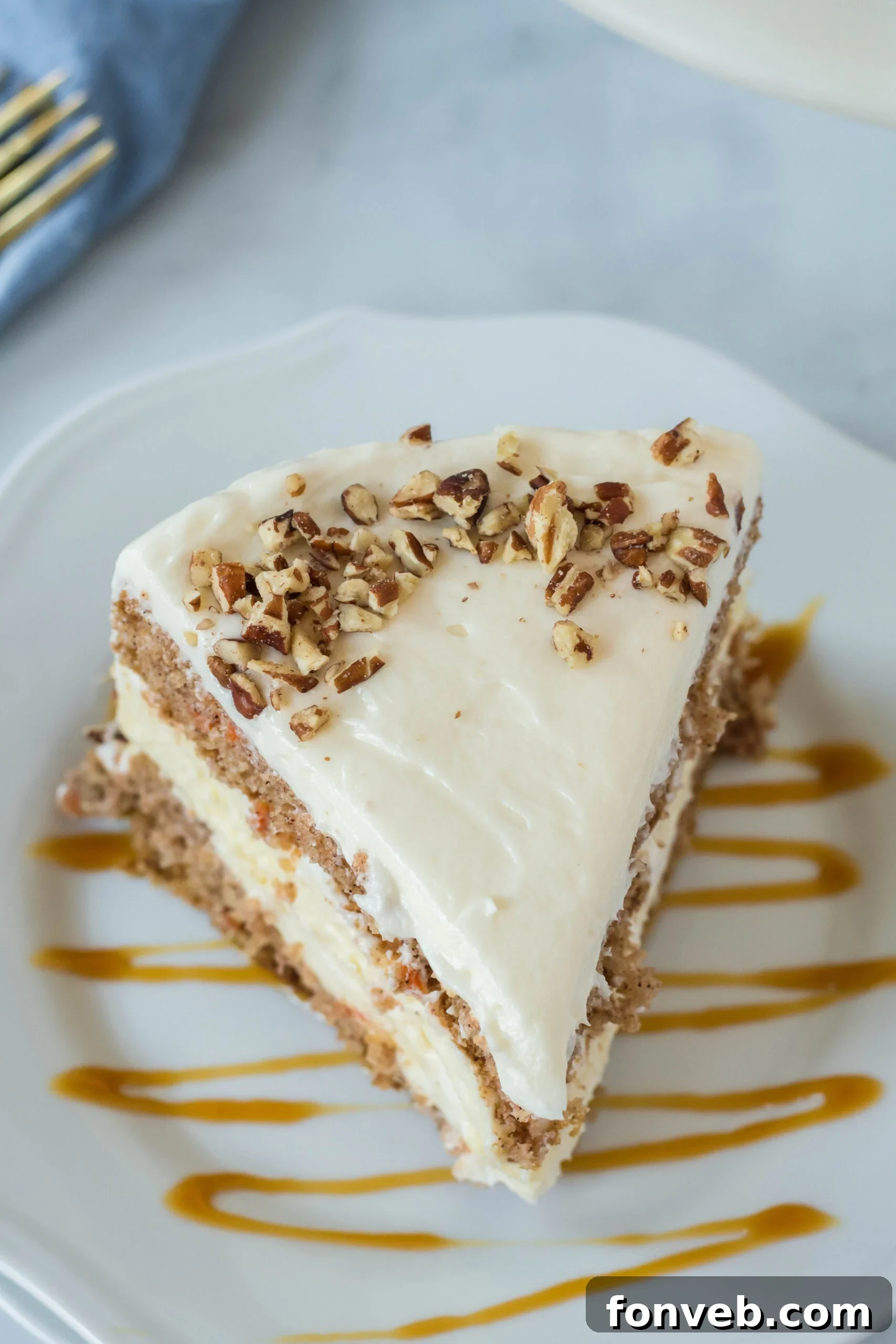 Overhead view of a slice of Carrot Cake Cheesecake on a white plate drizzled with caramel.