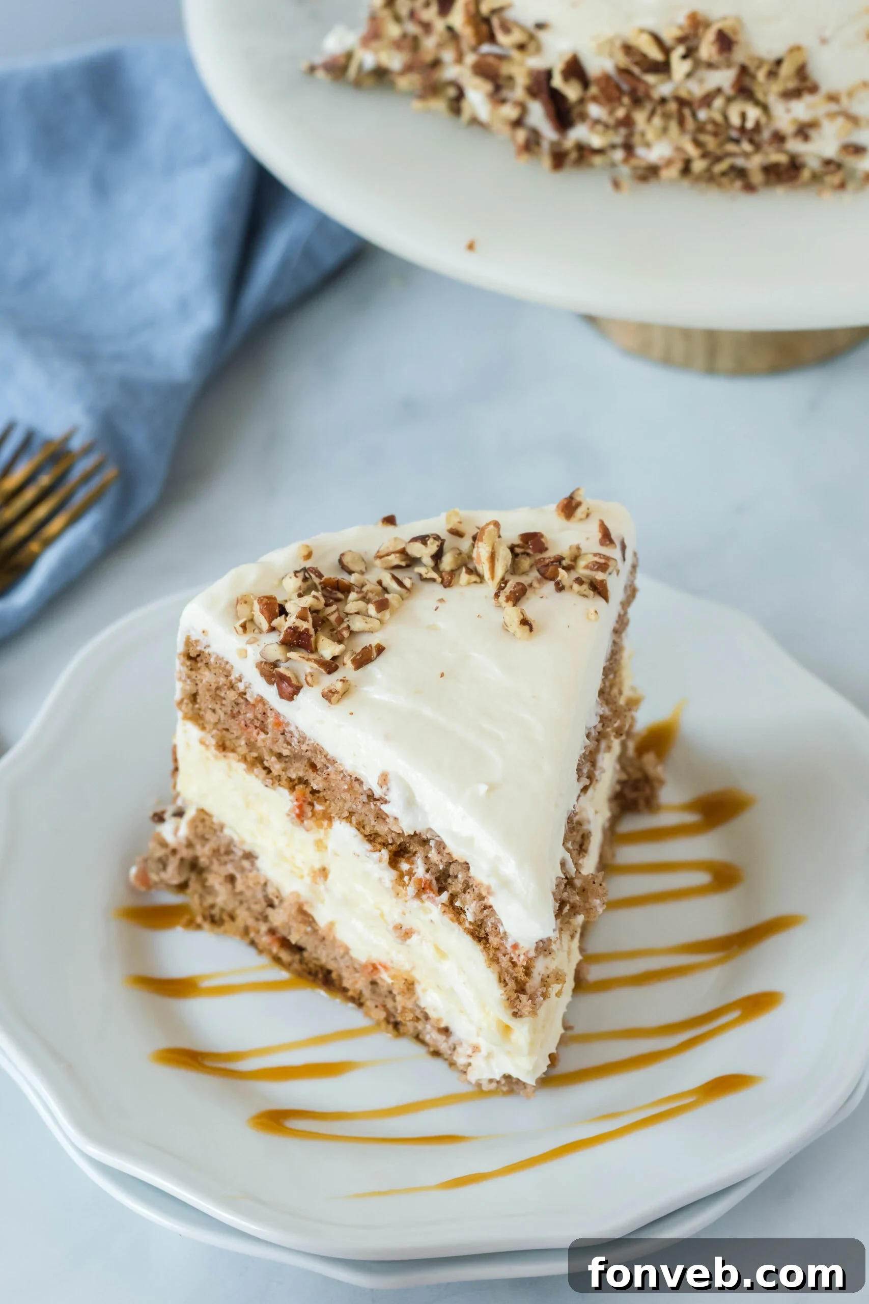 Front view of a slice of Carrot Cake Cheesecake on a white plate drizzled with caramel.