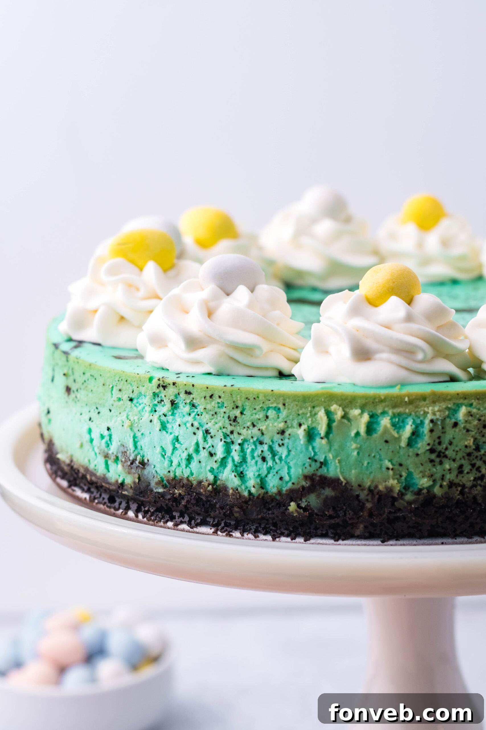 Front view of Speckled Egg Easter Cheesecake on a white cake stand, highlighting its elegant presentation.