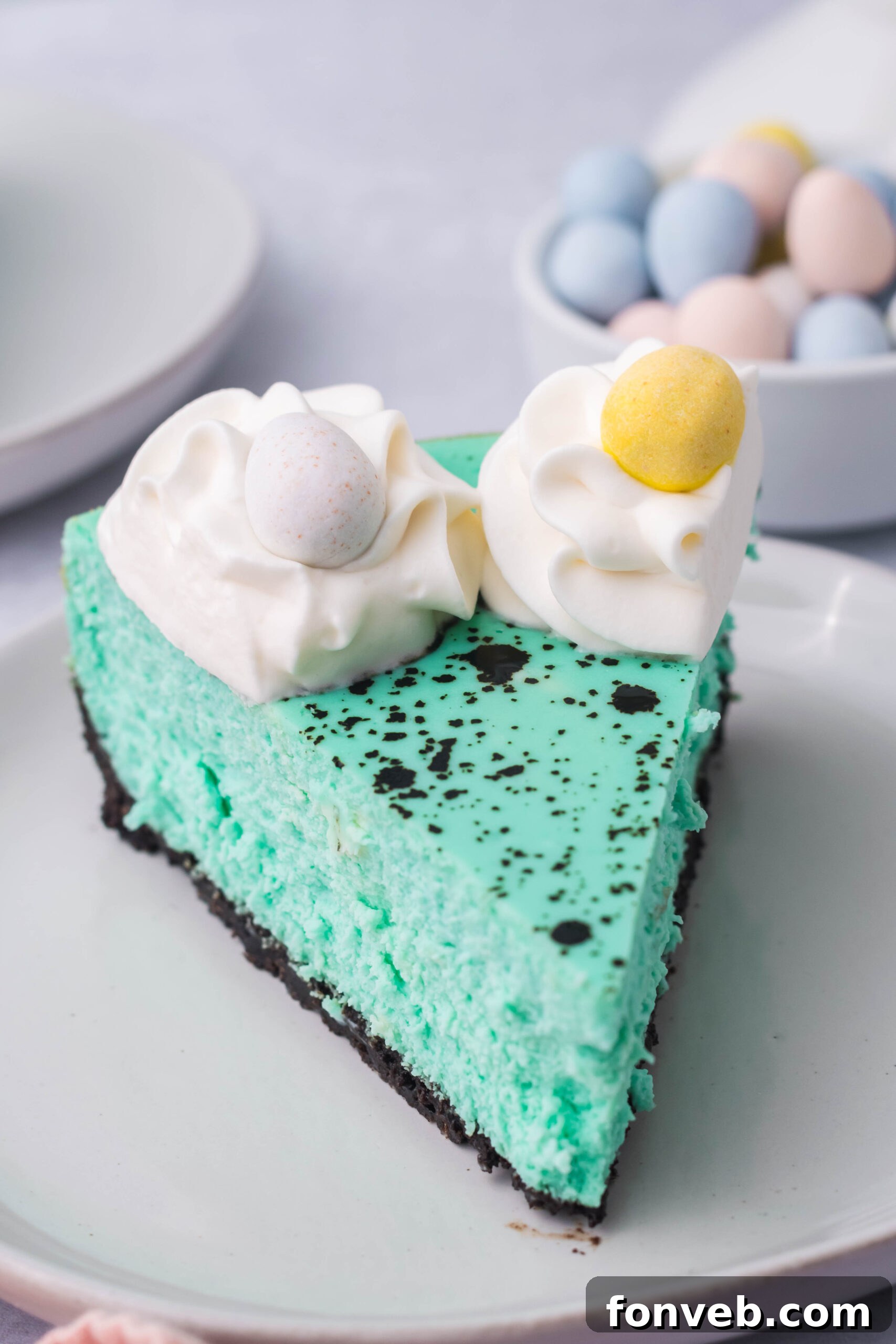 Front view of a slice of Speckled Egg Easter Cheesecake on a white plate, revealing the creamy texture.