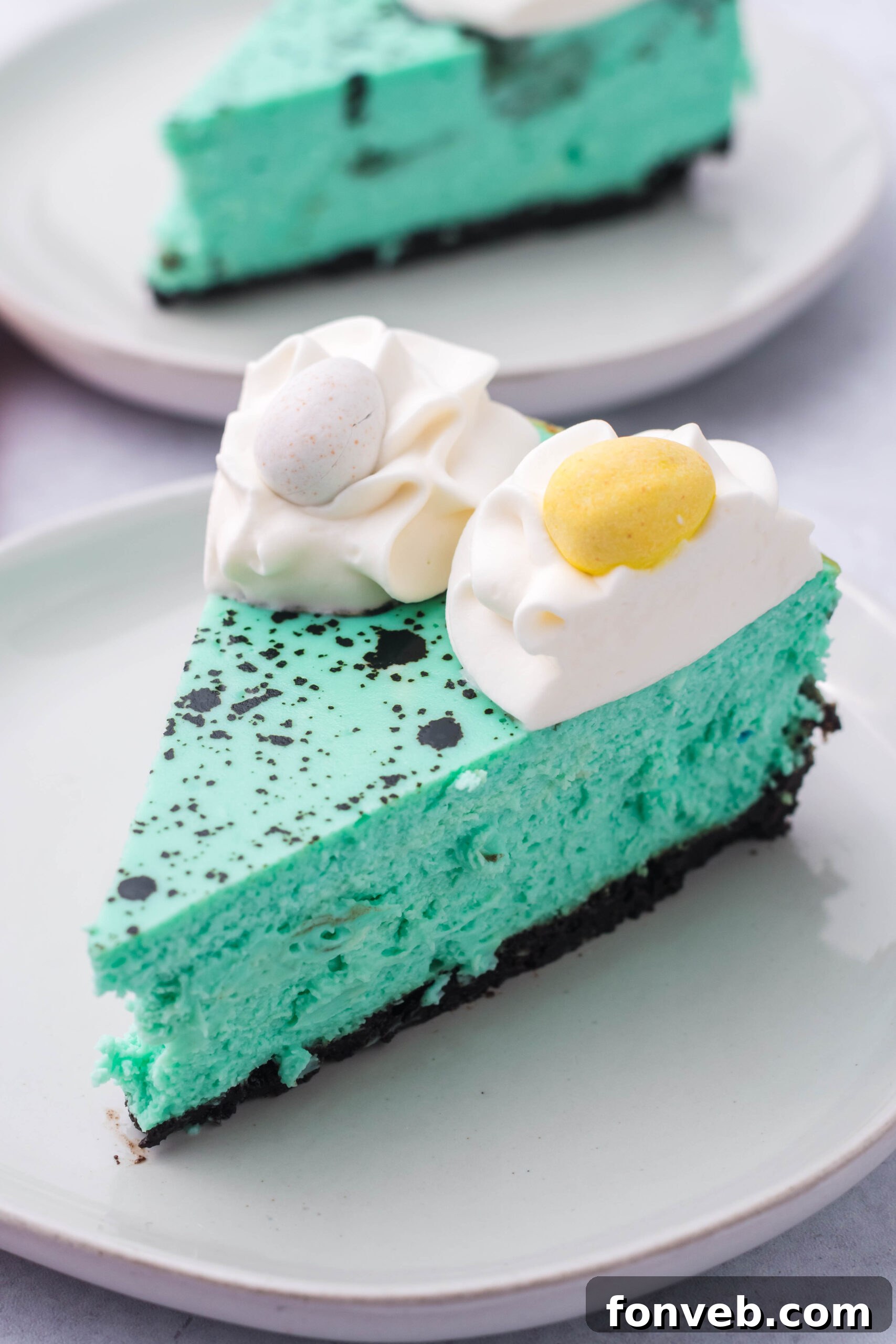 Side view of a slice of Speckled Egg Easter Cheesecake on a white plate, showing the layers.