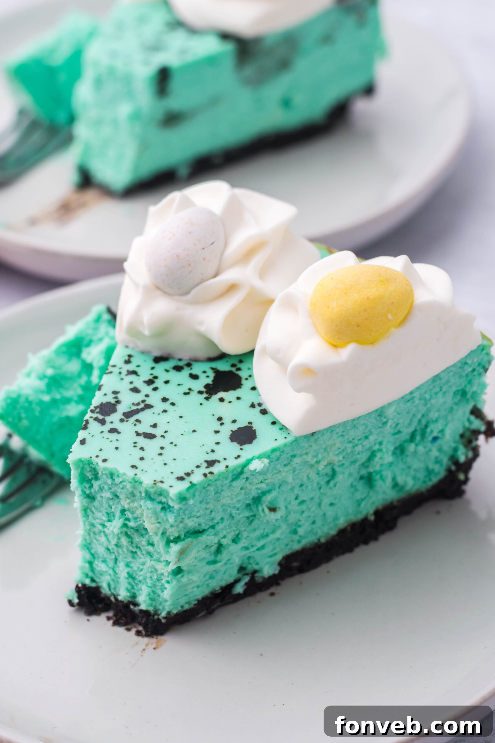 Side view of a slice of Speckled Egg Easter Cheesecake with a bite removed by a silver fork, showing its perfect layers.