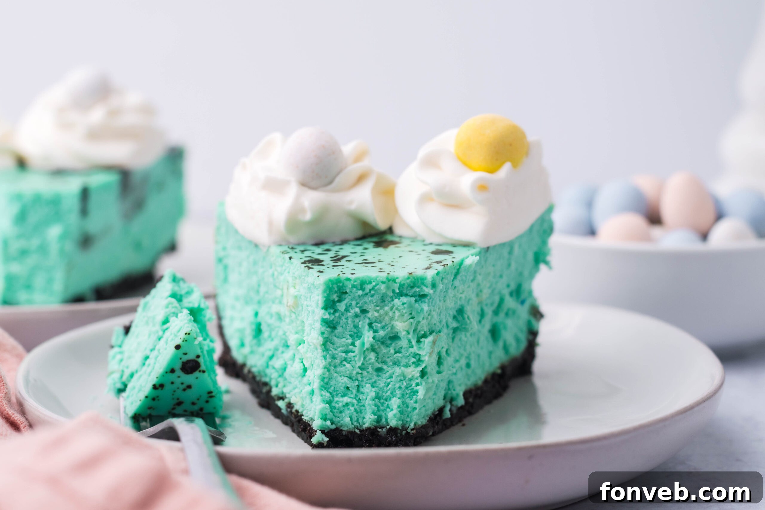 Front view of a slice of Speckled Egg Easter Cheesecake with a bite removed by a silver fork, emphasizing its delightful appearance.