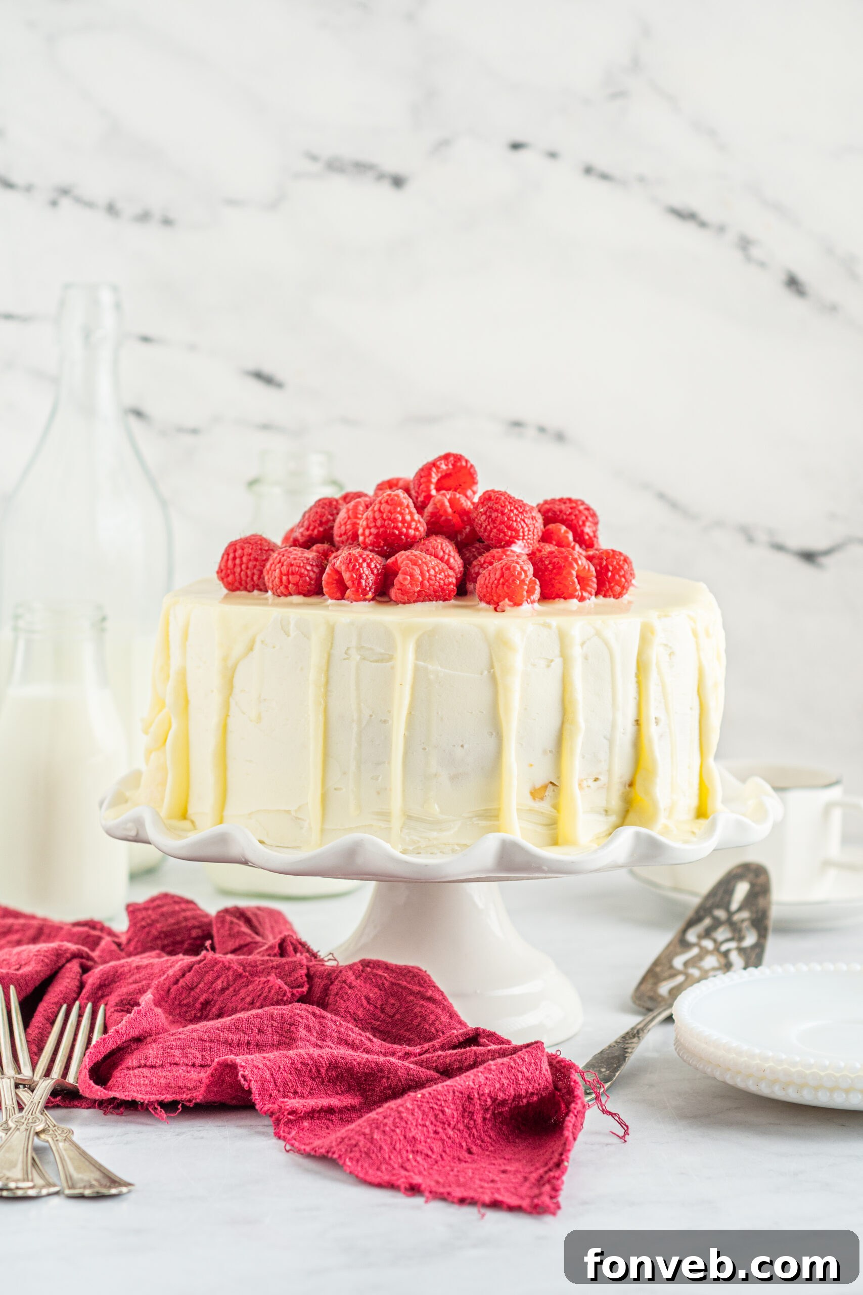 Front view of White Chocolate Cake with Raspberries on a white cake stand.