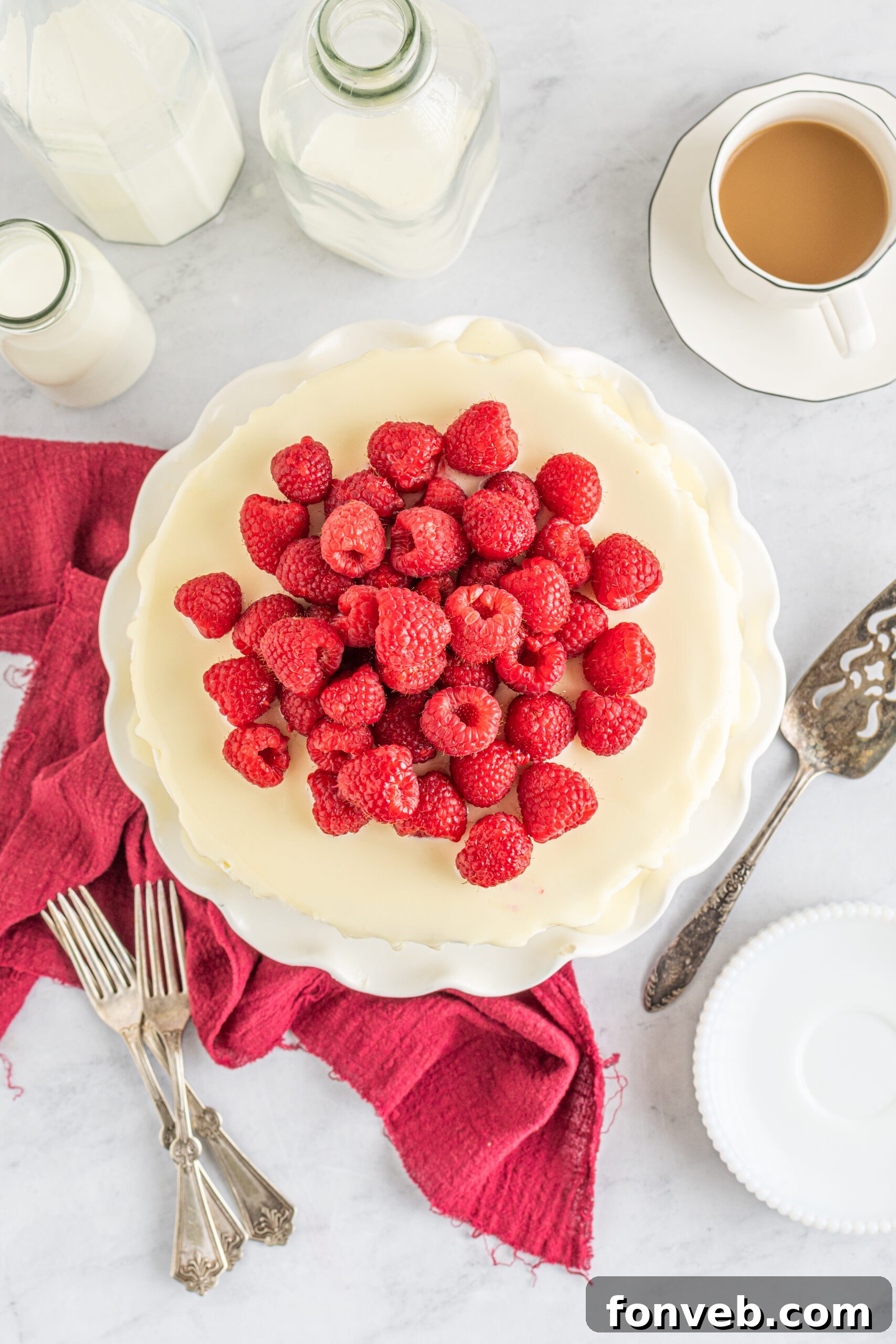 Overhead view of White Chocolate Cake with Raspberries on a white cake stand.