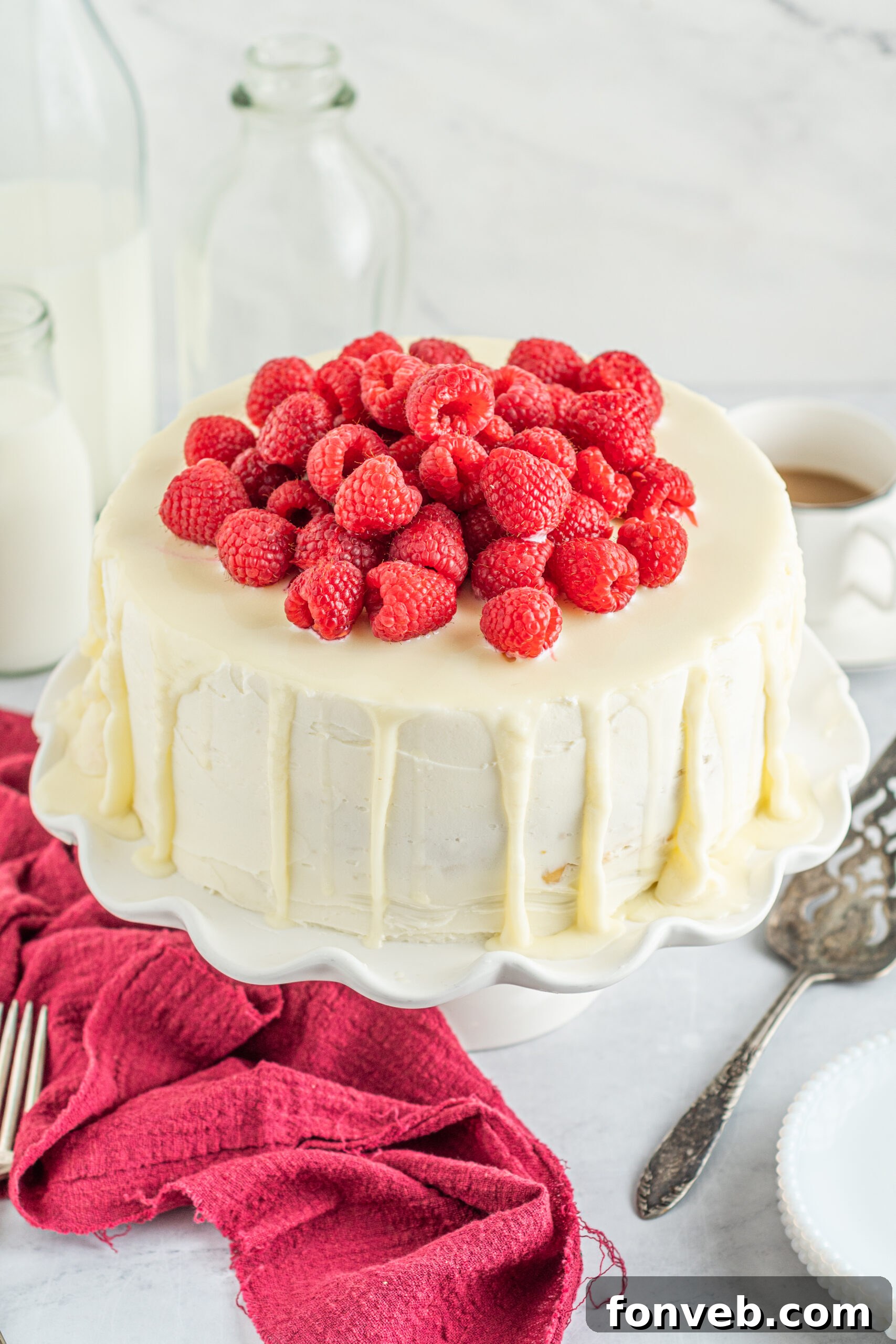 Front view of White Chocolate Cake with Raspberries on a white cake stand.