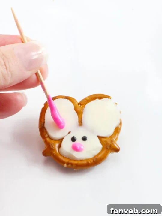 Hoppy Twists 7 A freshly dipped pretzel twist resting on parchment paper, awaiting decoration, showing the smooth white chocolate coating.
