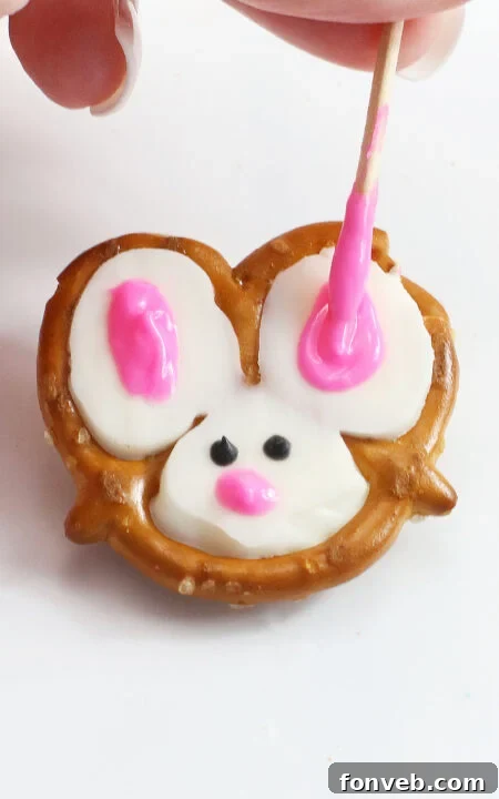 Hoppy Twists 8 An assortment of decorated Bunny Pretzels drying on parchment paper, displaying varying stages of completion.