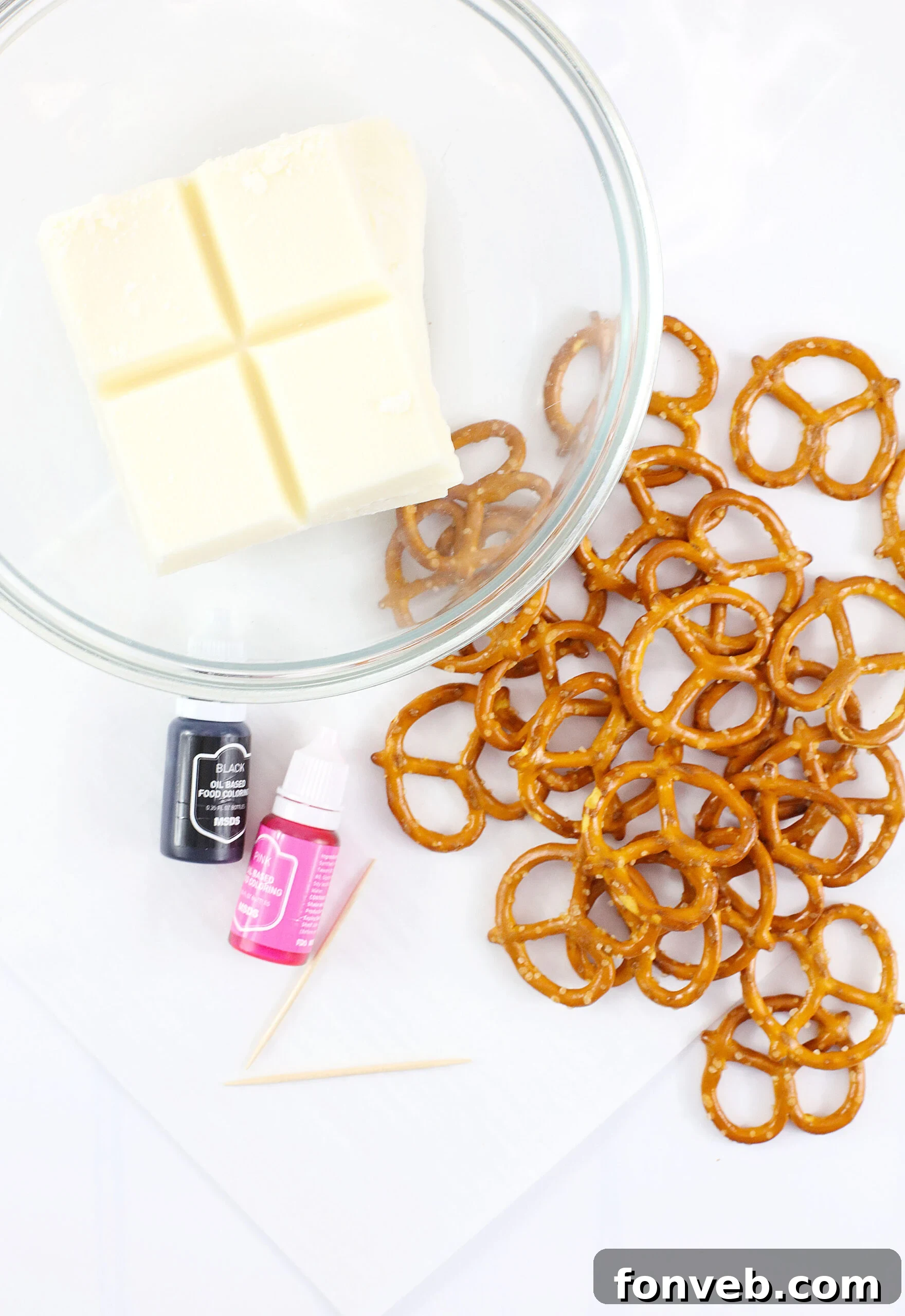 Hoppy Twists 10 An organized overhead display of all ingredients laid out, including white chocolate almond bark, pretzel twists, and food coloring, ready for the Bunny Pretzel recipe.